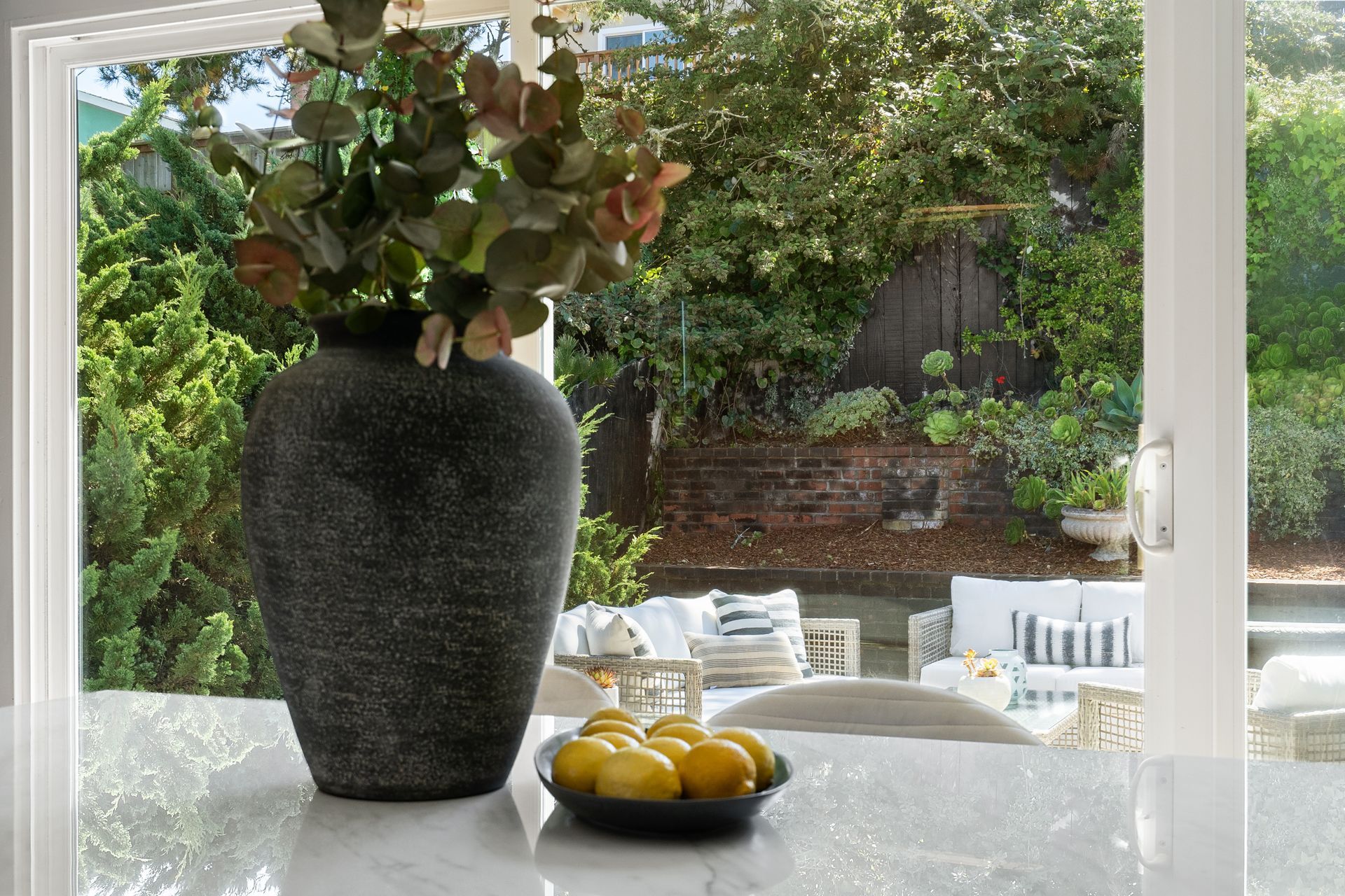 A vase of flowers is sitting on a table next to a bowl of lemons.