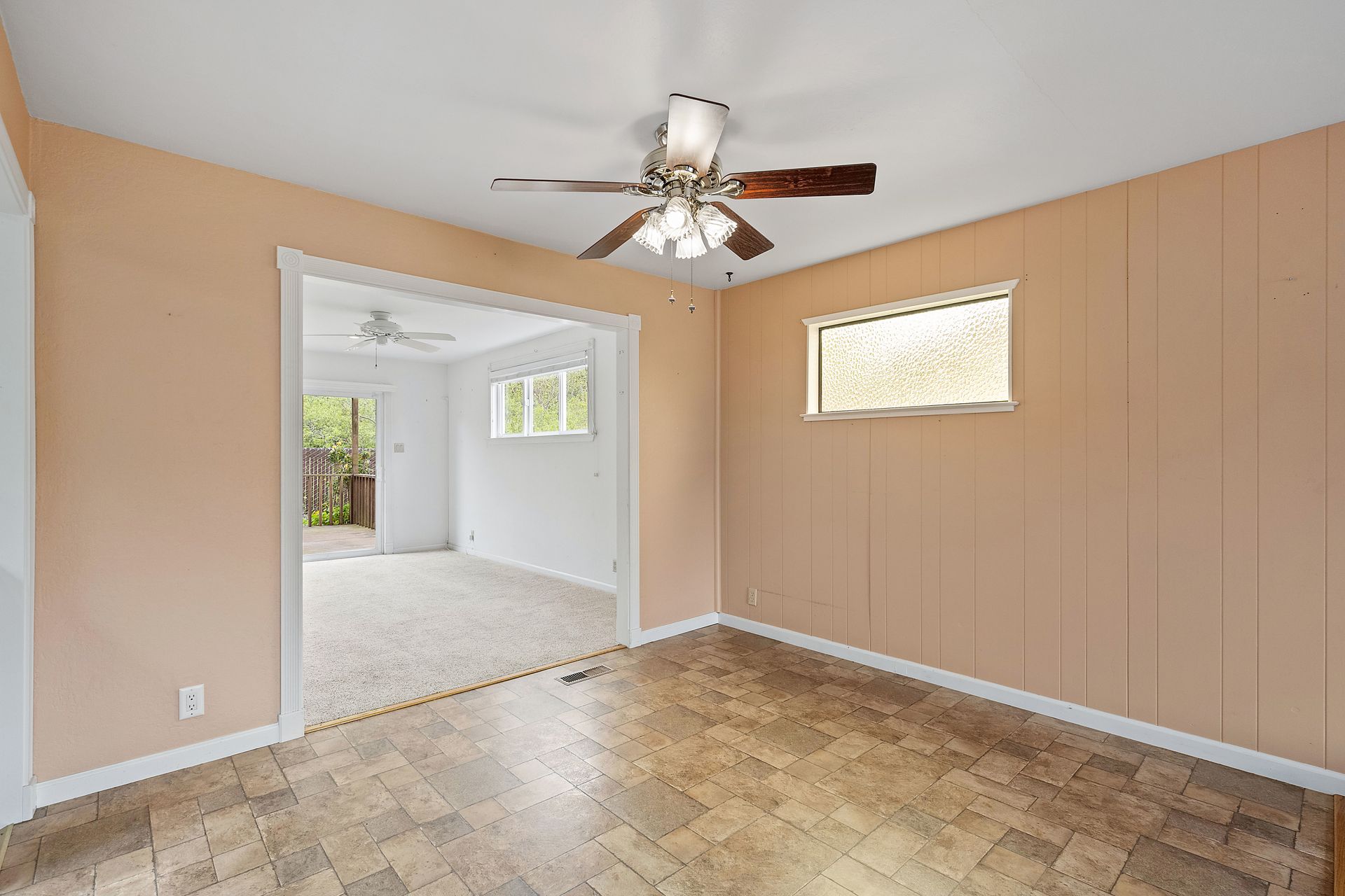 An empty room with a ceiling fan and a window.