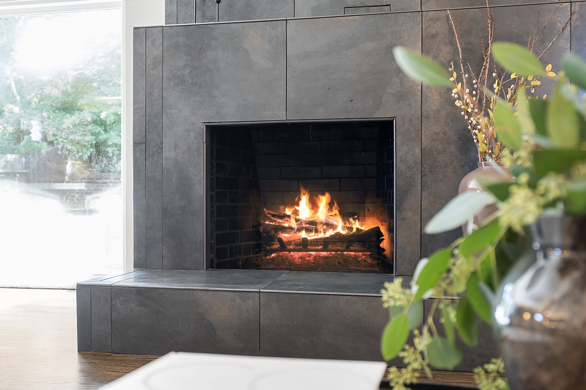 A living room with a fireplace and a vase of flowers.