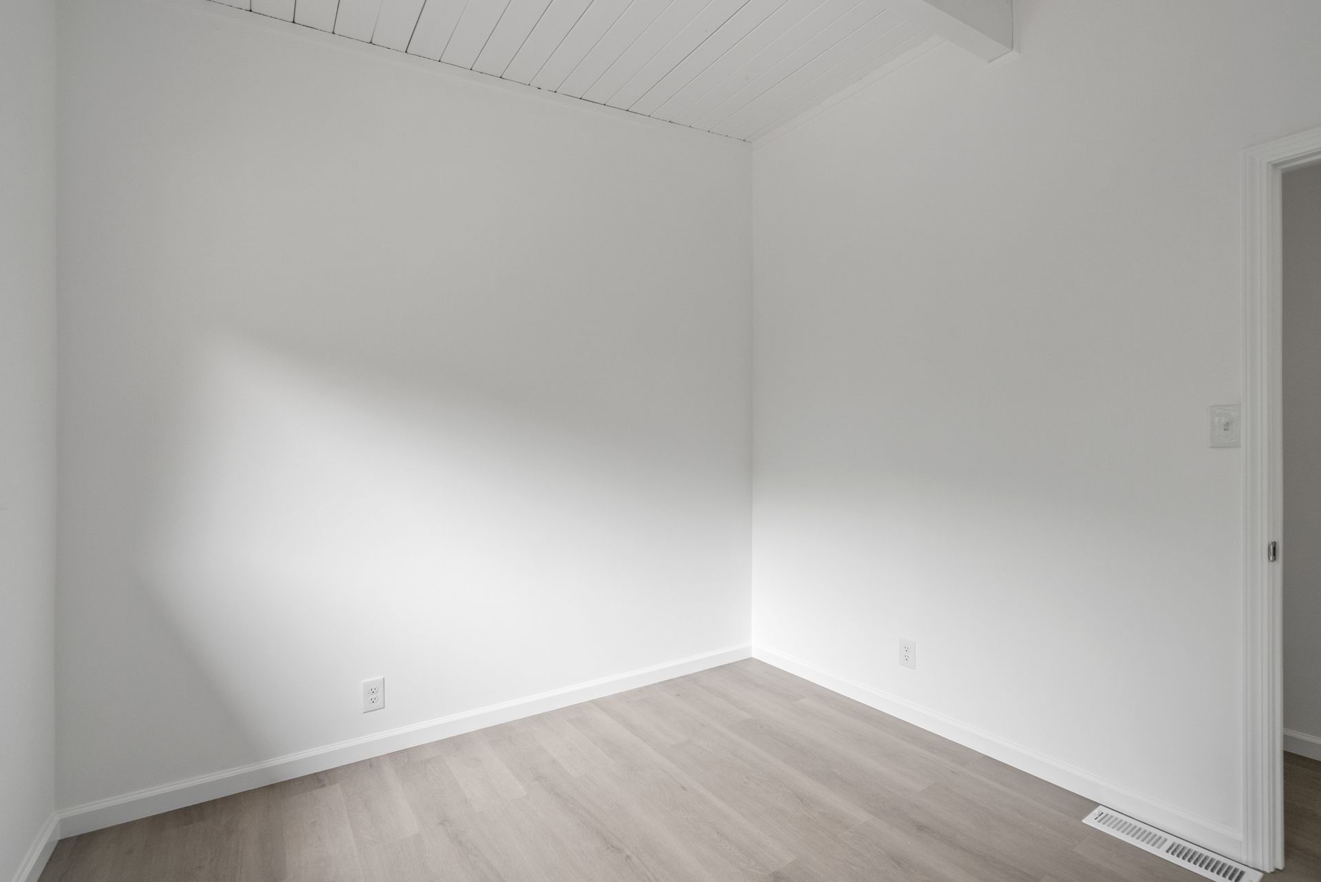 An empty room with white walls and a wooden floor.