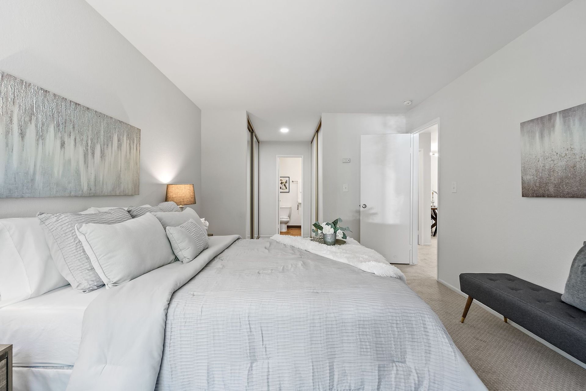 A bedroom with a bed and a bench.