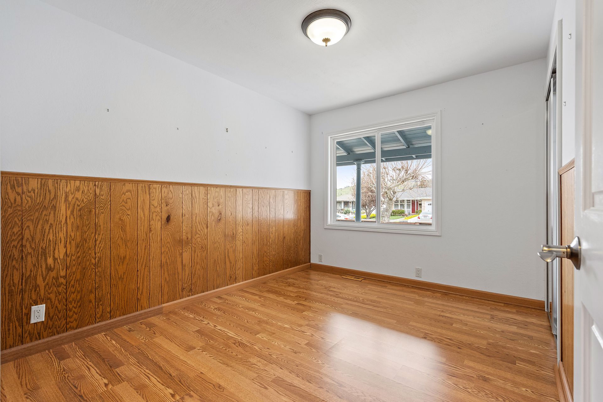 An empty room with hardwood floors and a window.