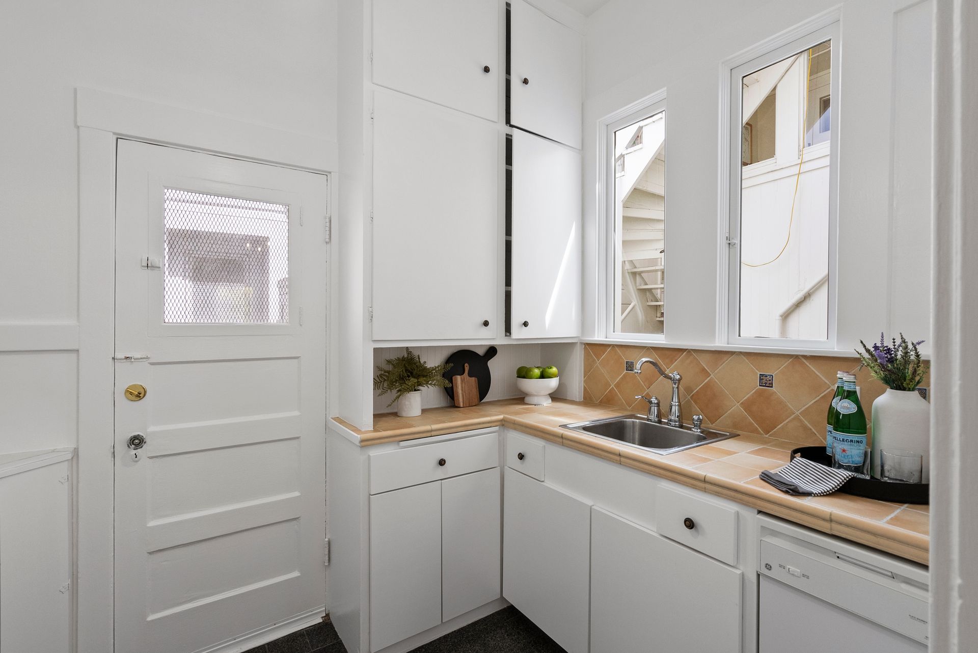 A kitchen with white cabinets and a sink.