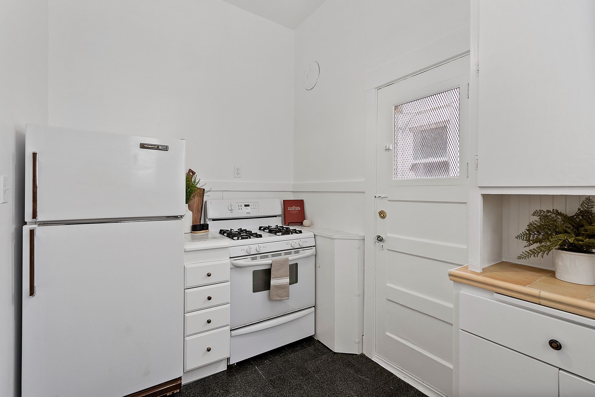 A kitchen with a white refrigerator , stove , and cabinets.