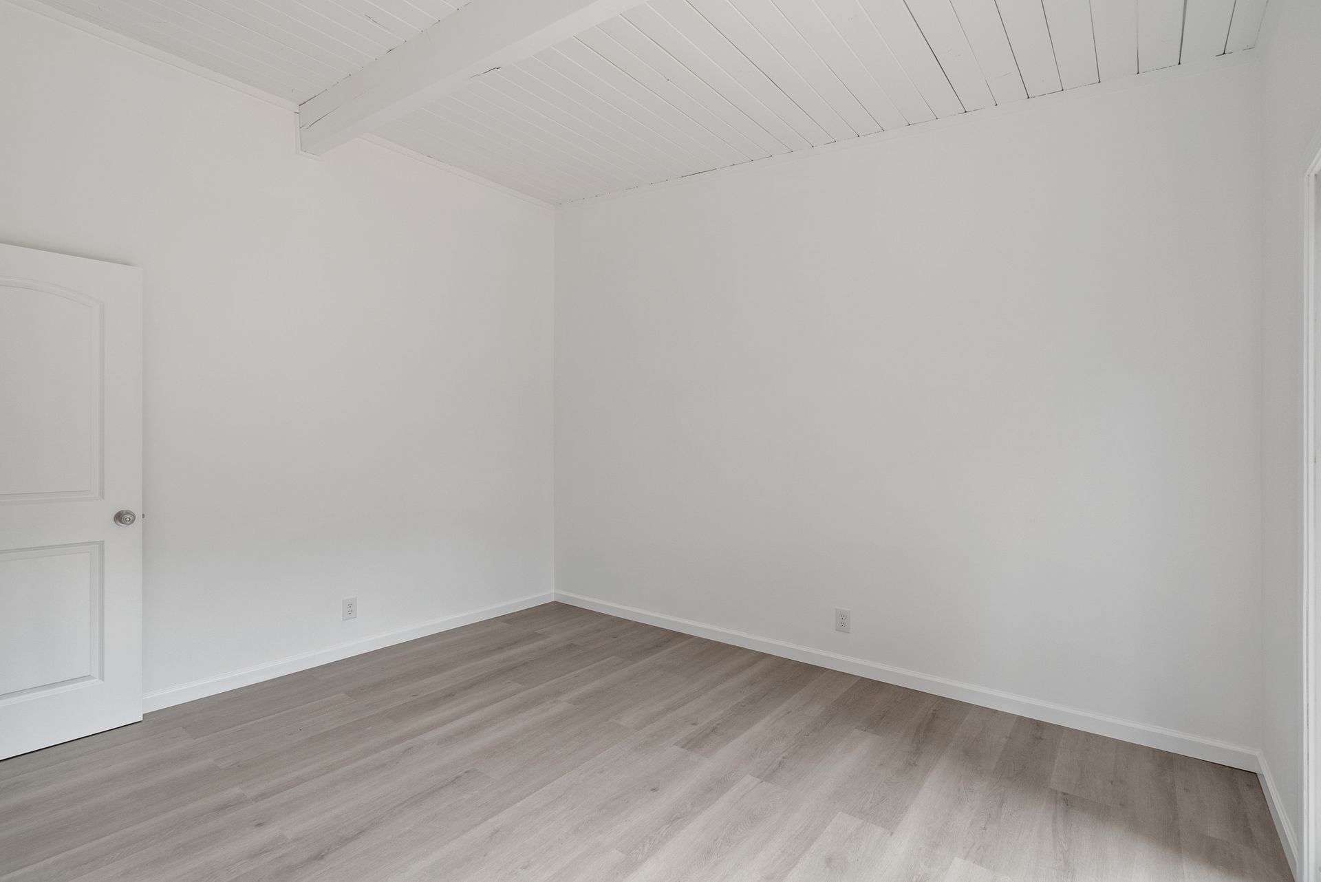 An empty room with white walls and wooden floors.
