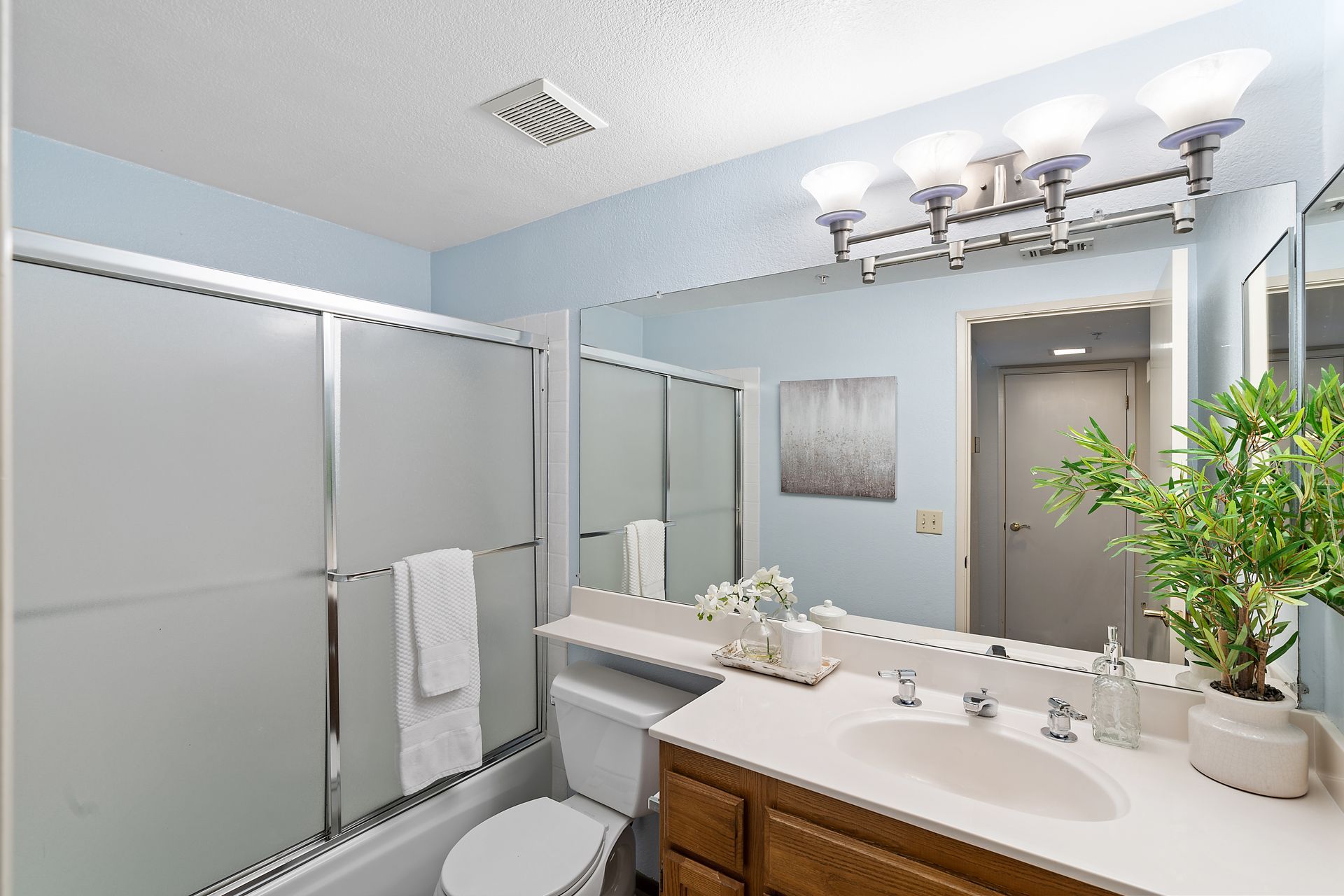 A bathroom with a sink , toilet , shower and mirror.
