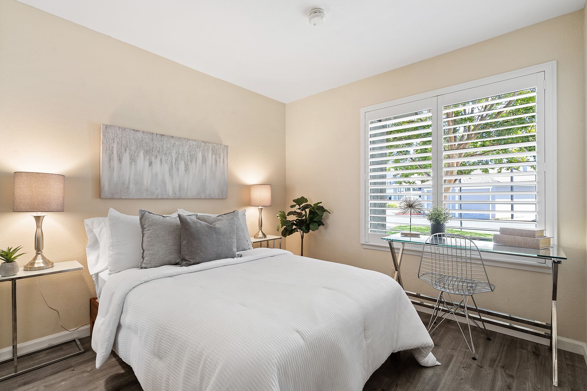 A bedroom with a bed , desk , lamps and a window.