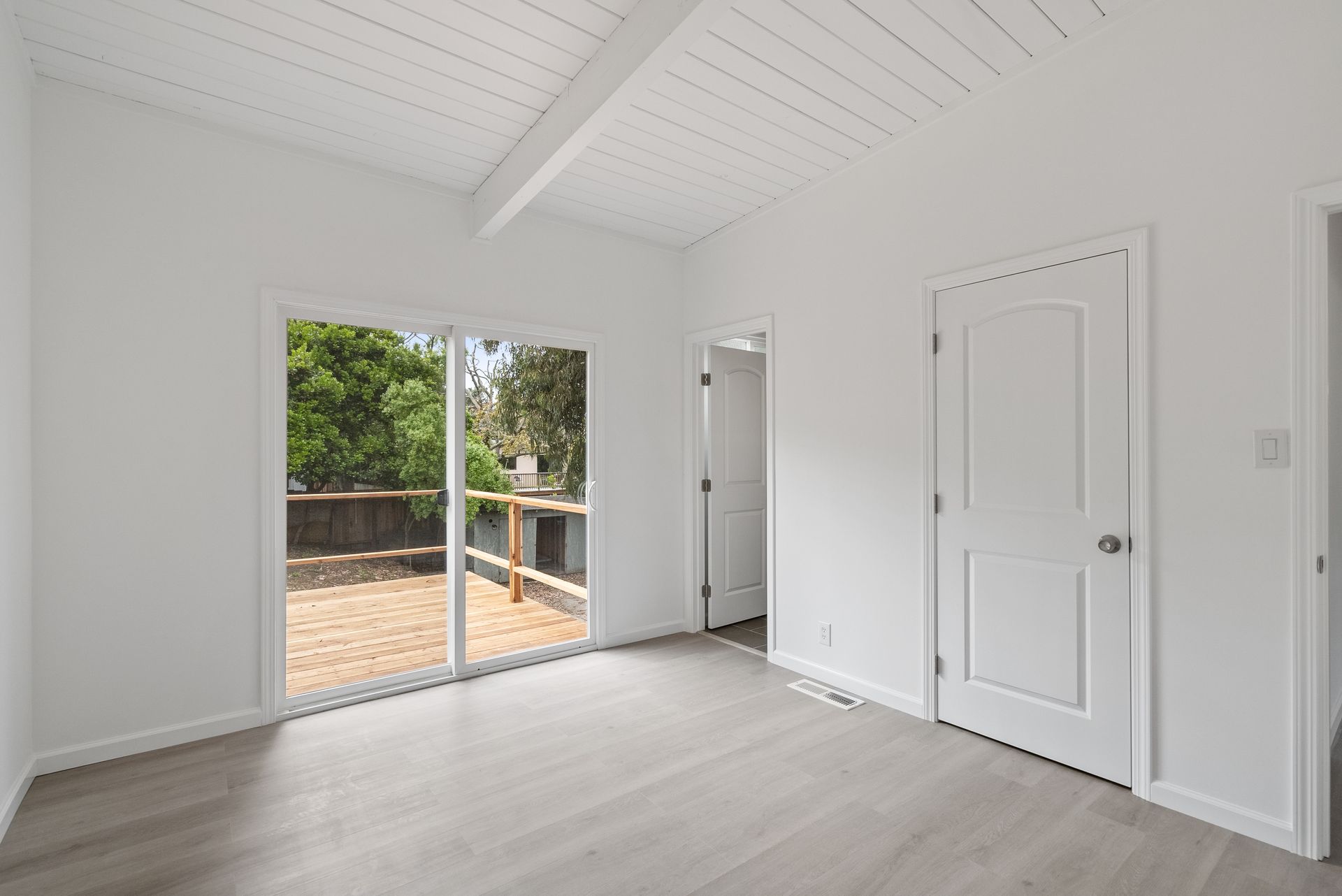 An empty room with a sliding glass door leading to a deck.