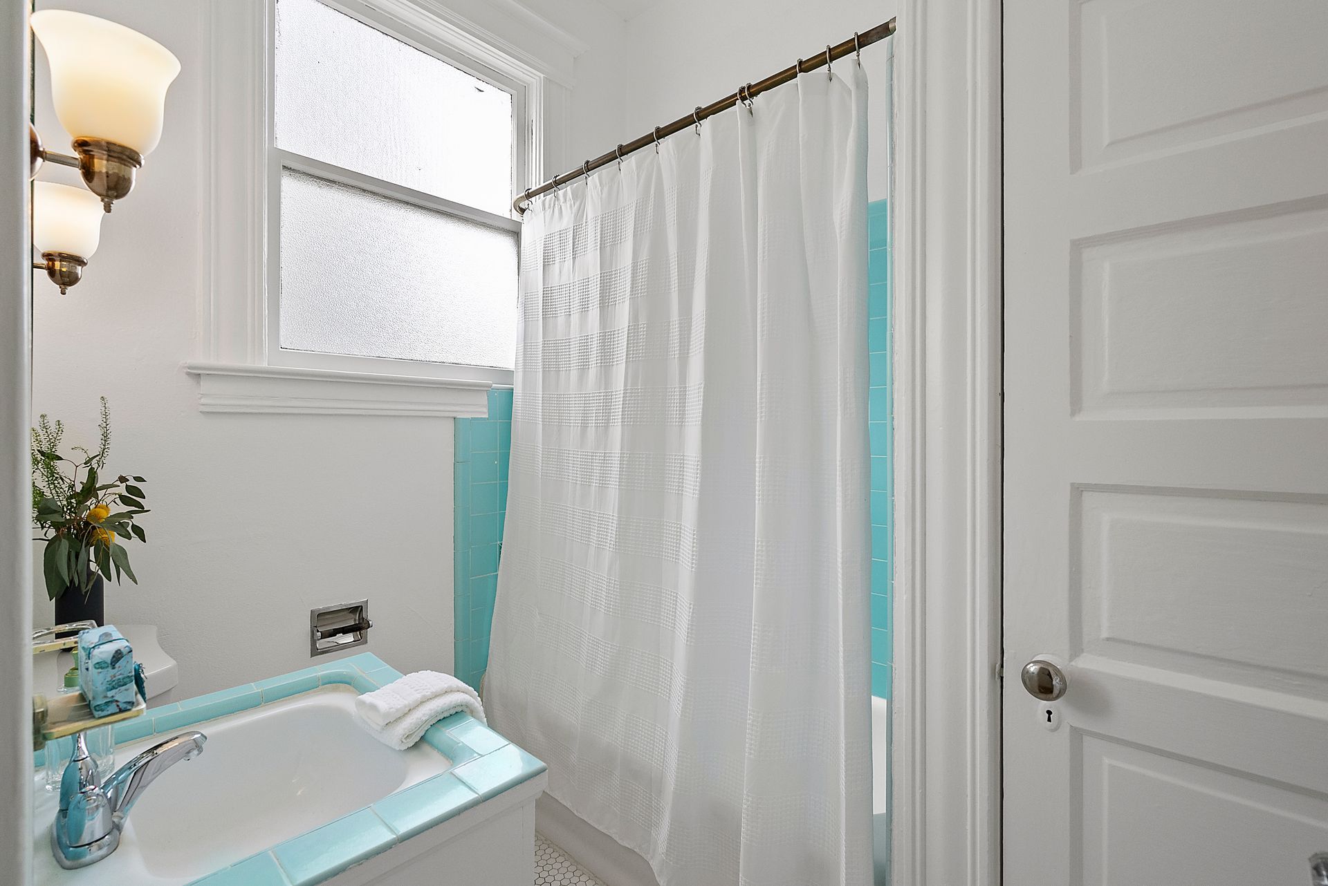 A bathroom with a tub , sink and shower curtain.