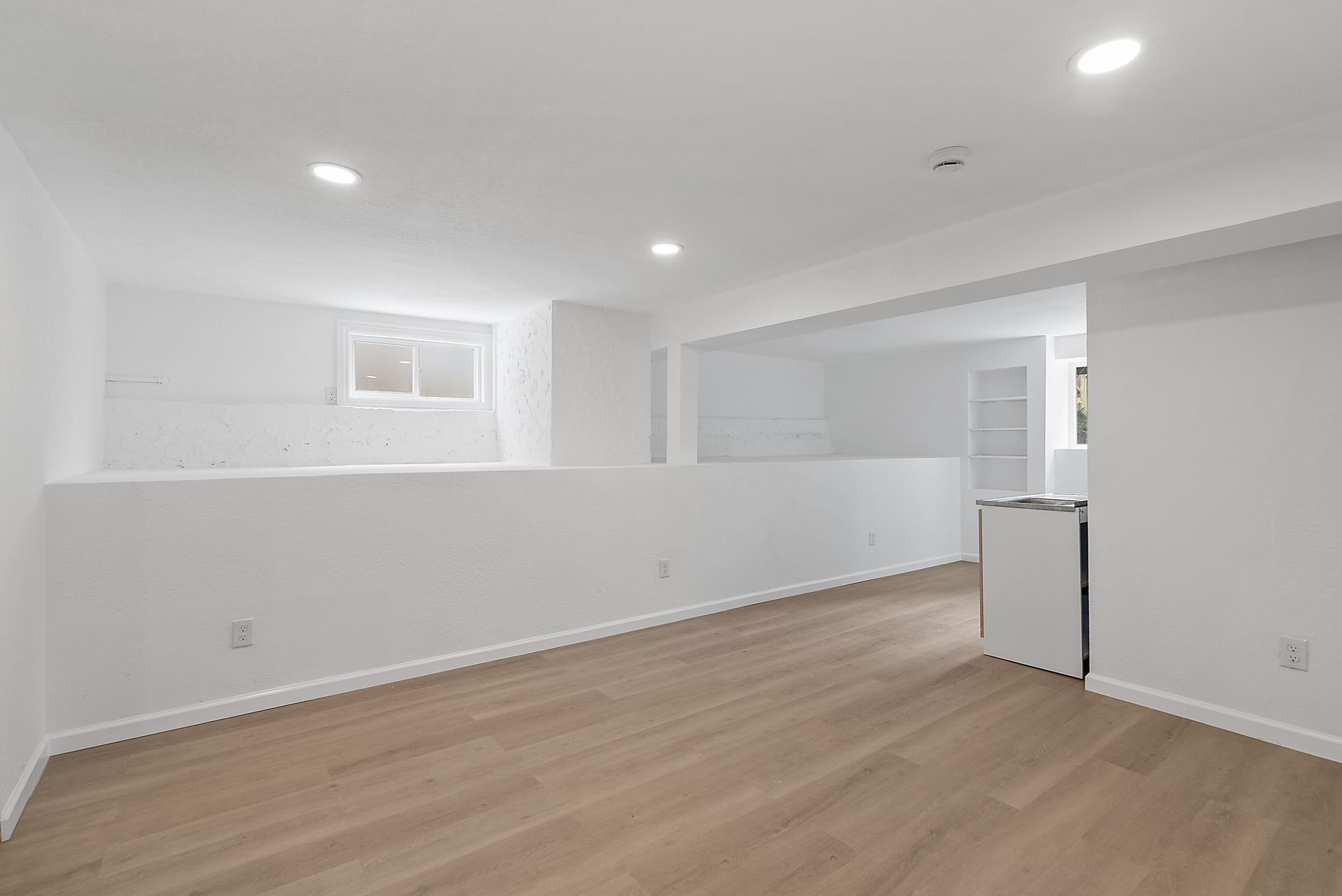 An empty room with hardwood floors and white walls.