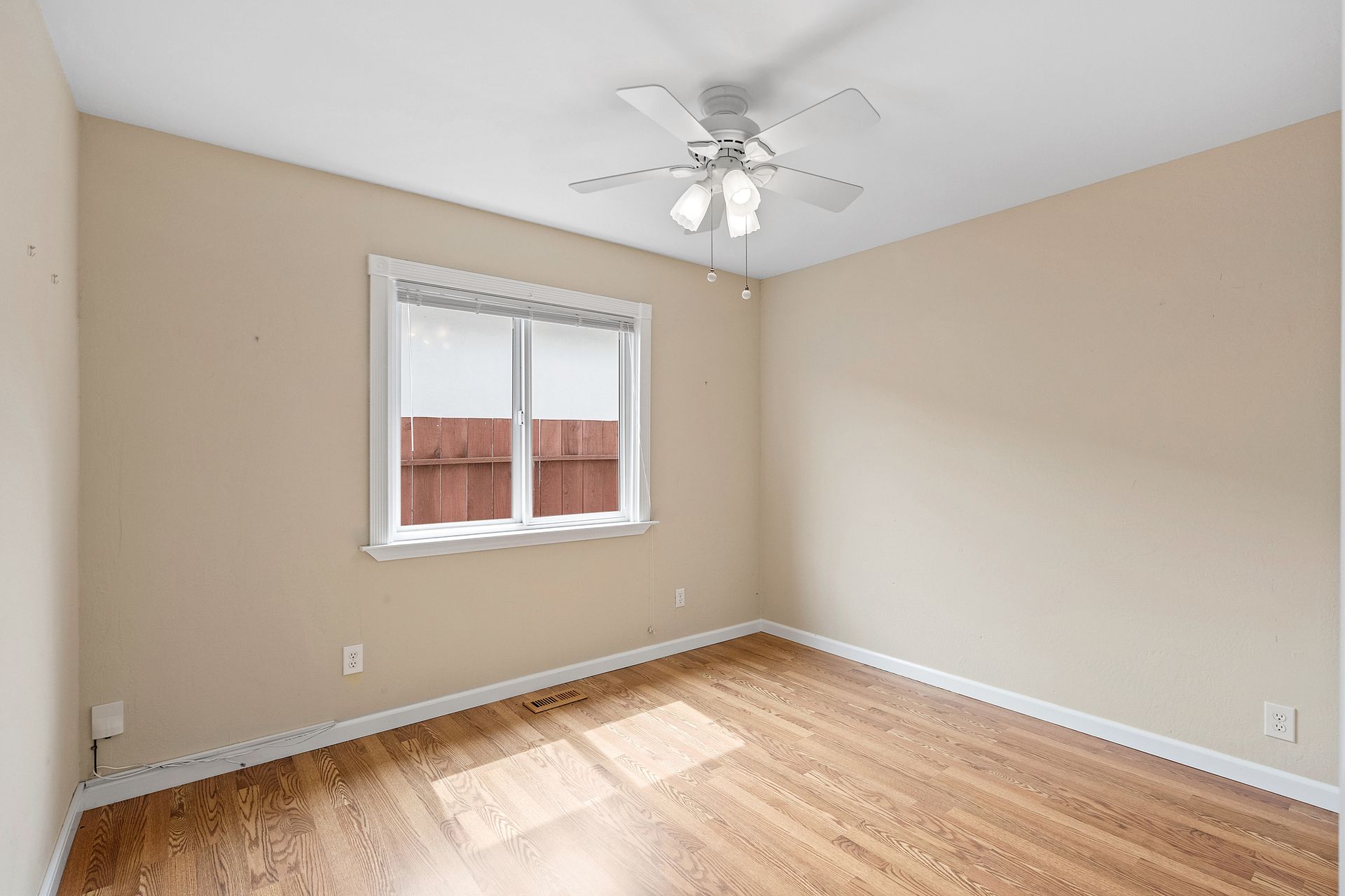An empty bedroom with a ceiling fan and a window.