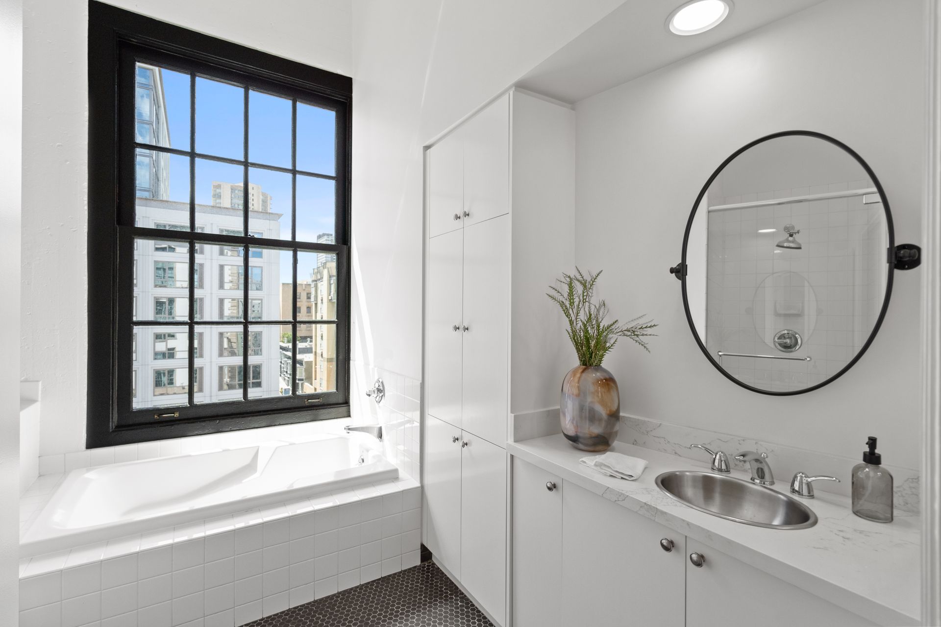 A bathroom with a bathtub and a sink and has a large window