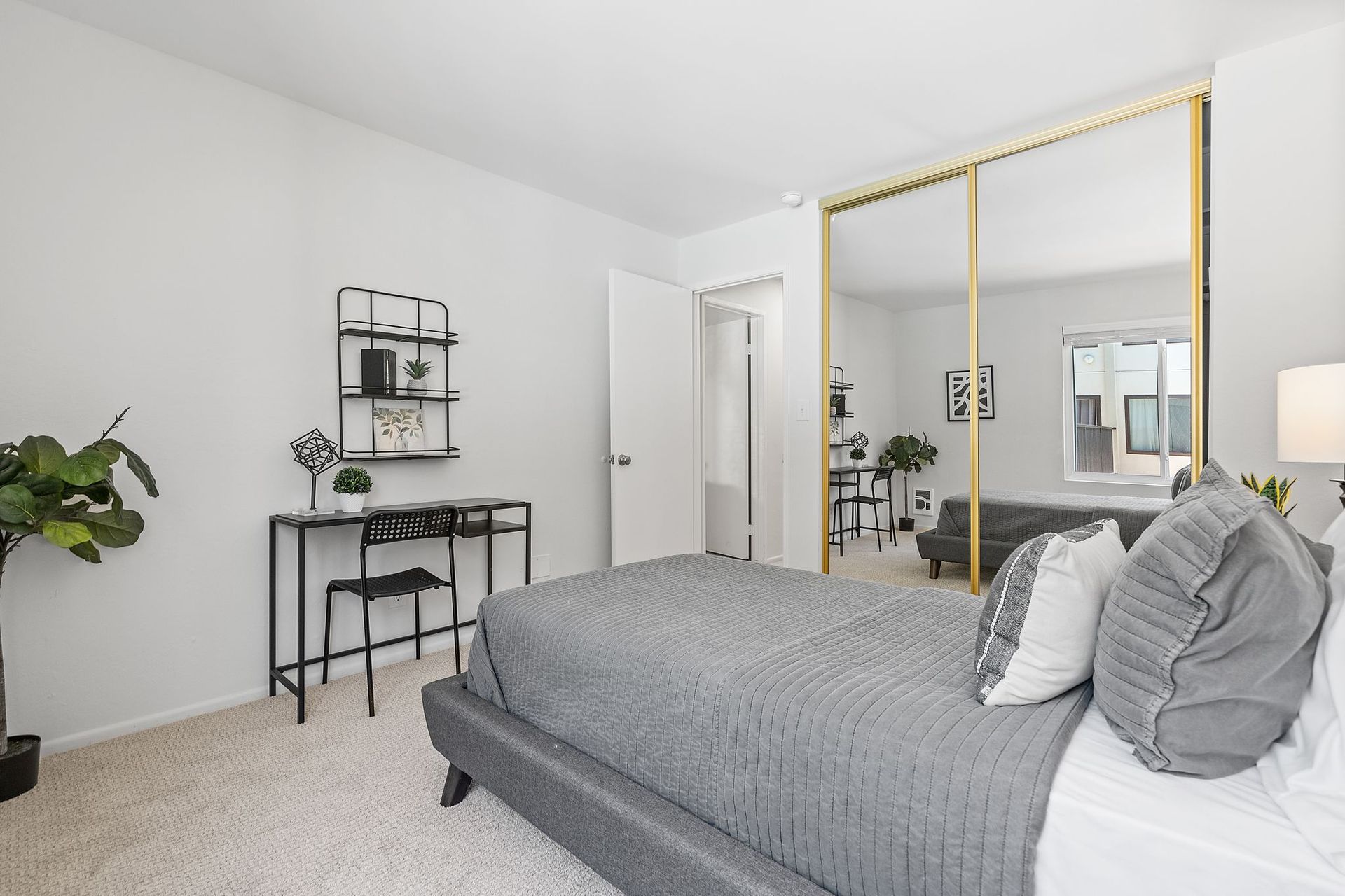 A bedroom with a bed , desk , and sliding glass doors.