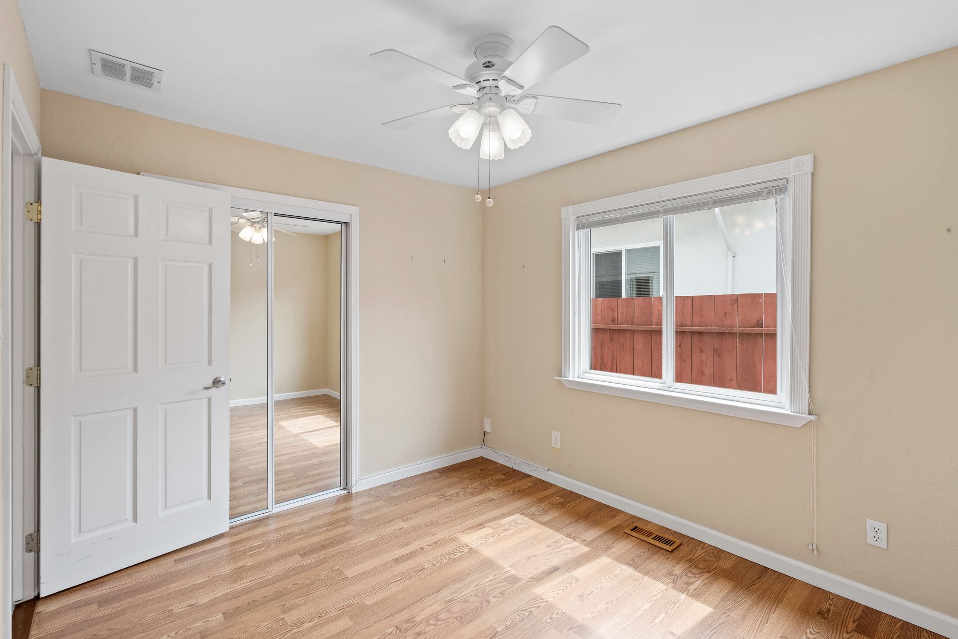An empty bedroom with a ceiling fan and a window