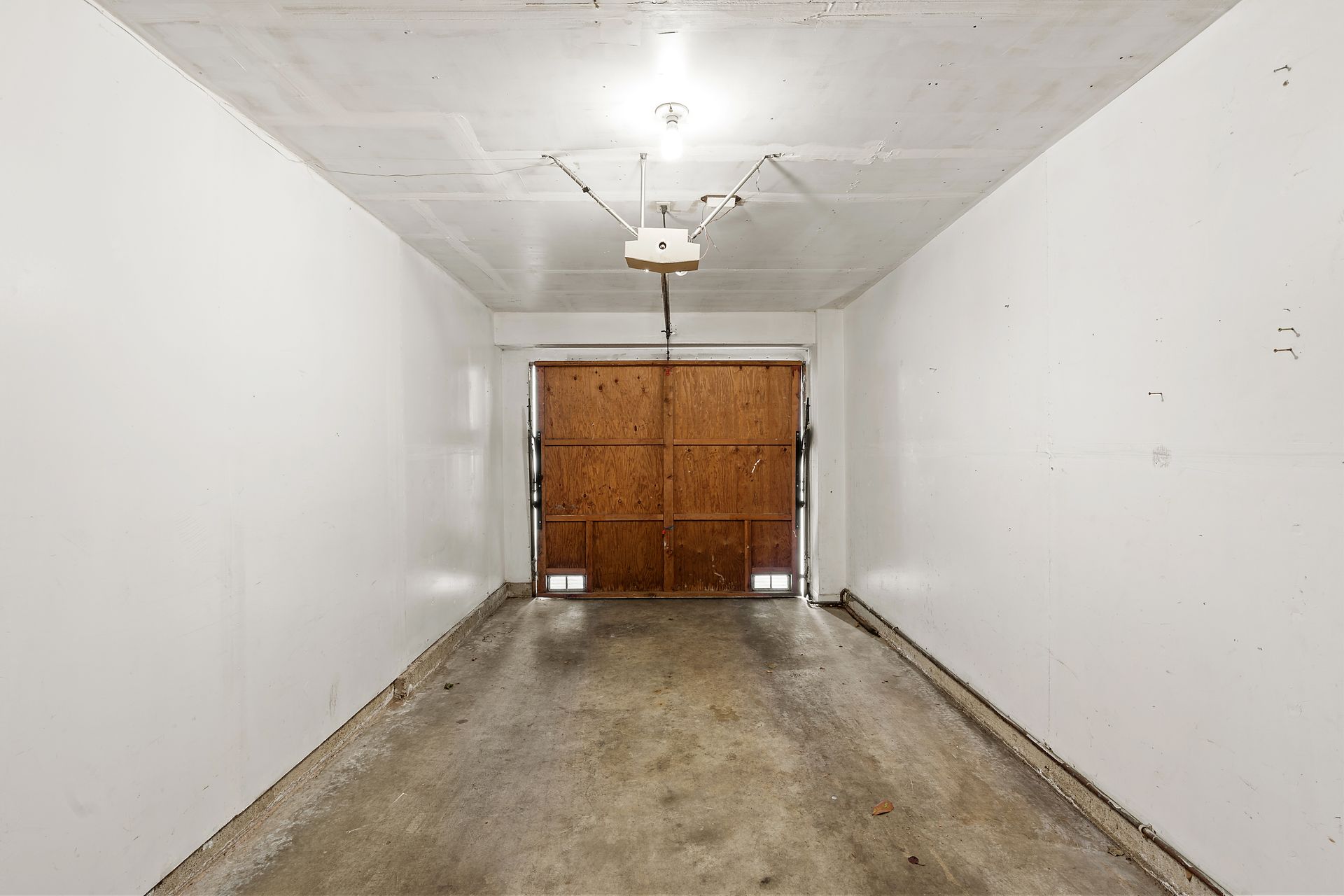 An empty garage with a wooden garage door and a garage door opener.