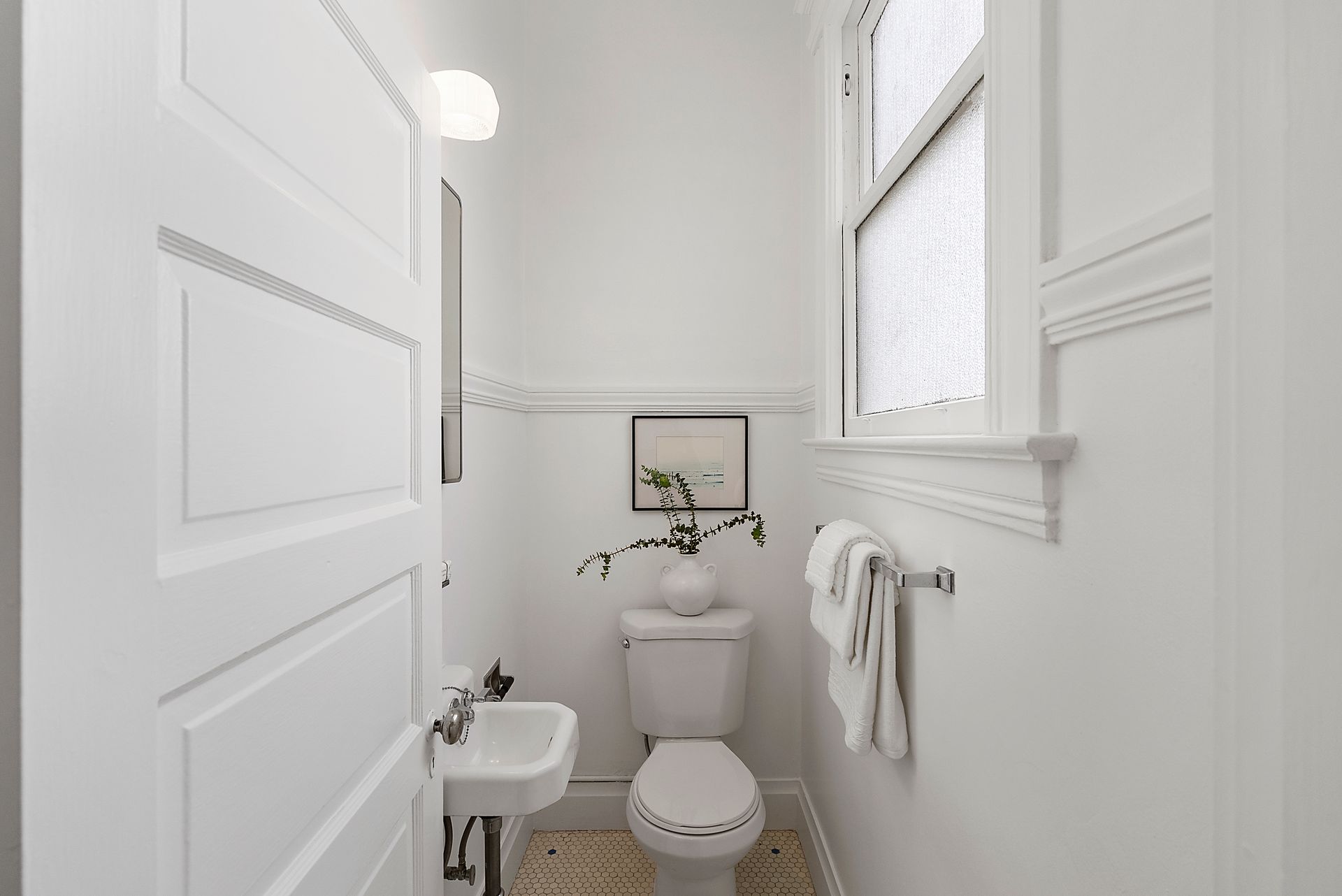 A bathroom with a toilet , sink and window.
