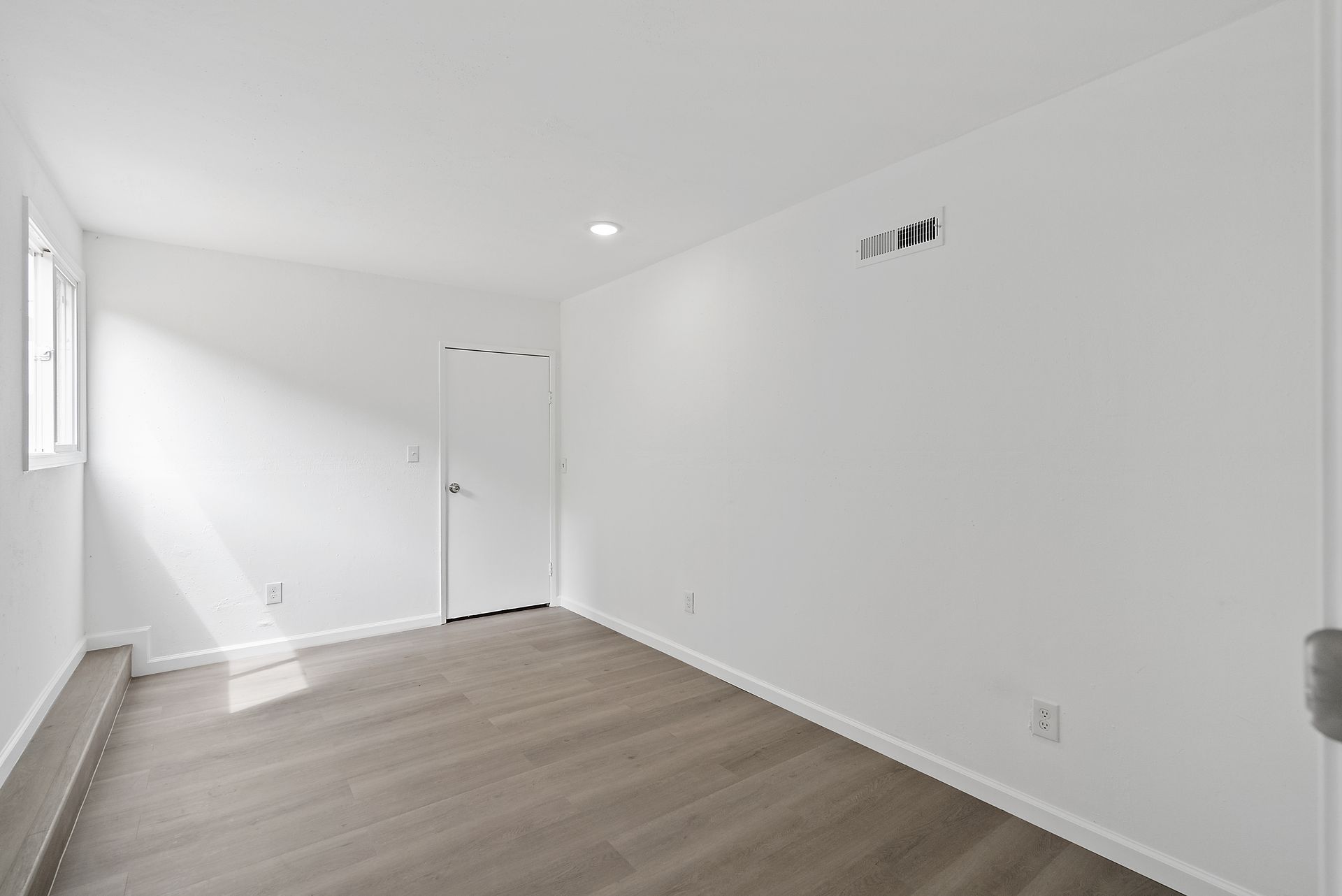 An empty room with hardwood floors and white walls.