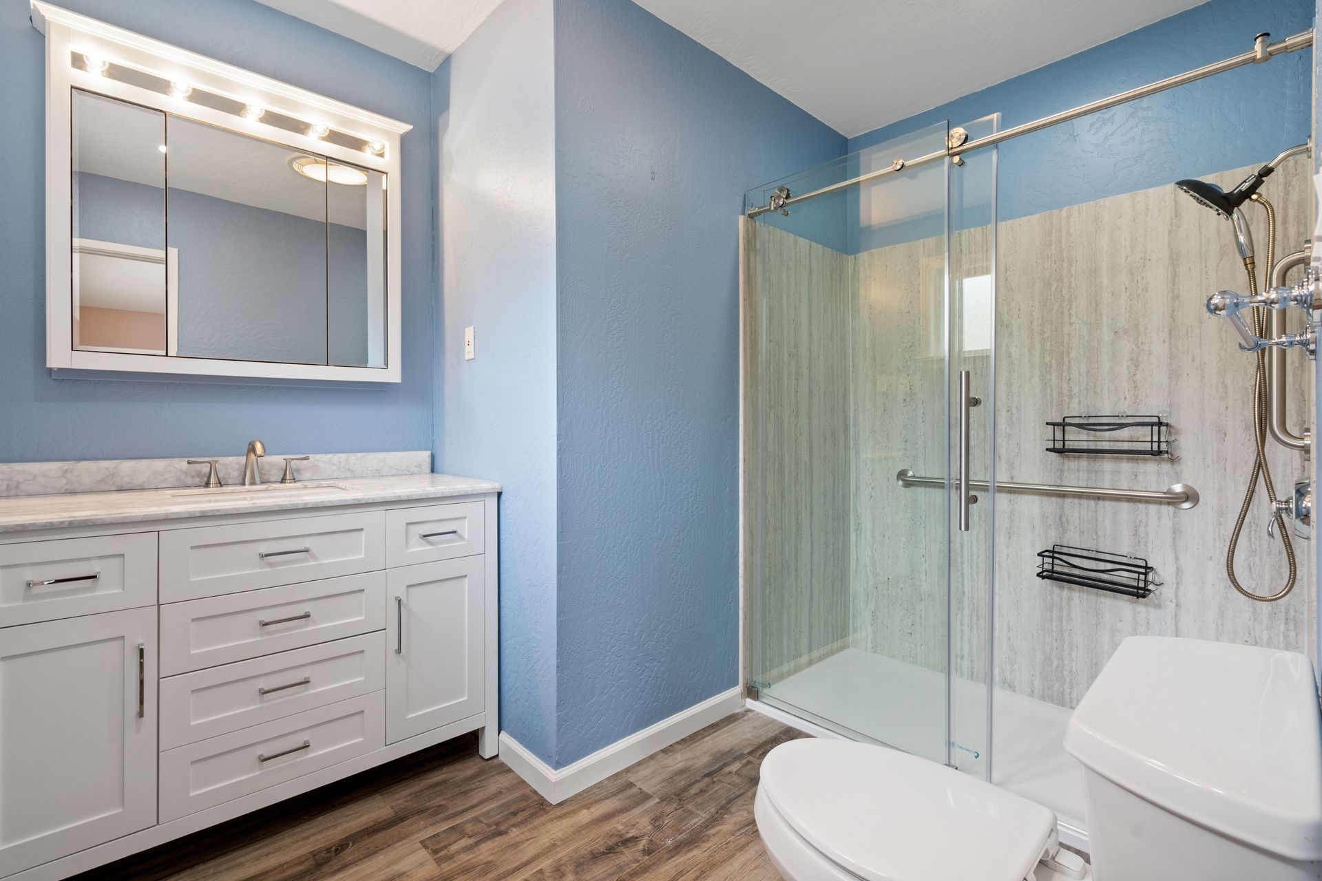 A bathroom with a toilet , sink , mirror and shower stall.