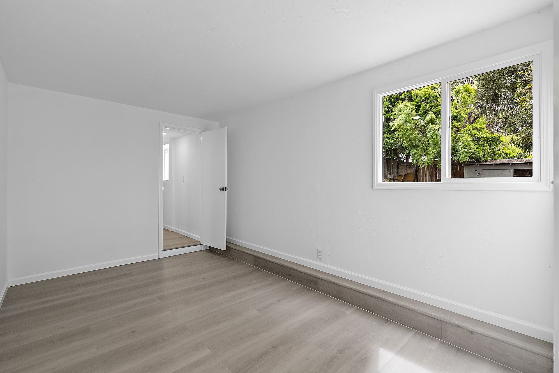 An empty room with windows and a wooden floor.