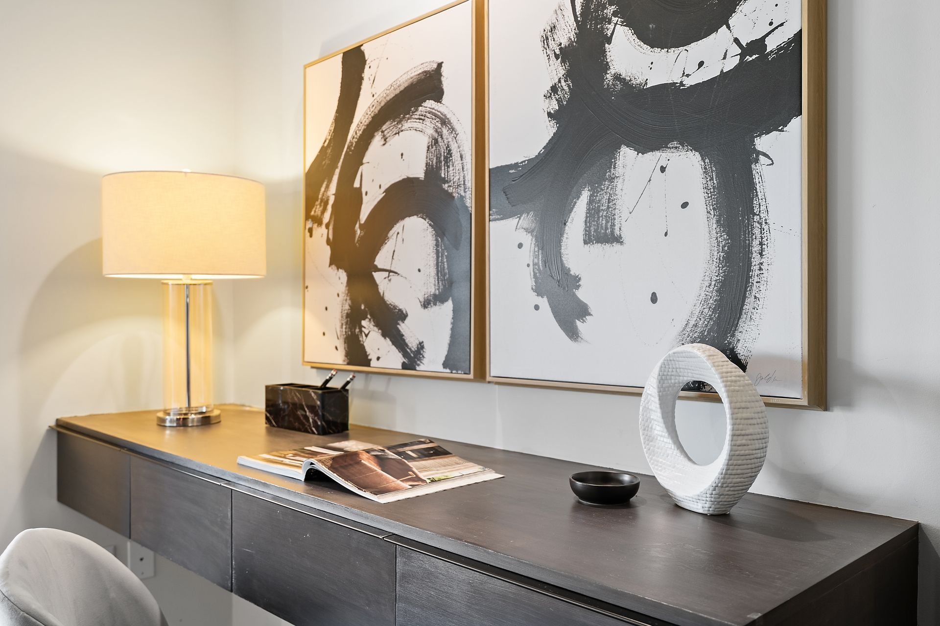 There are two paintings on the wall above the desk.