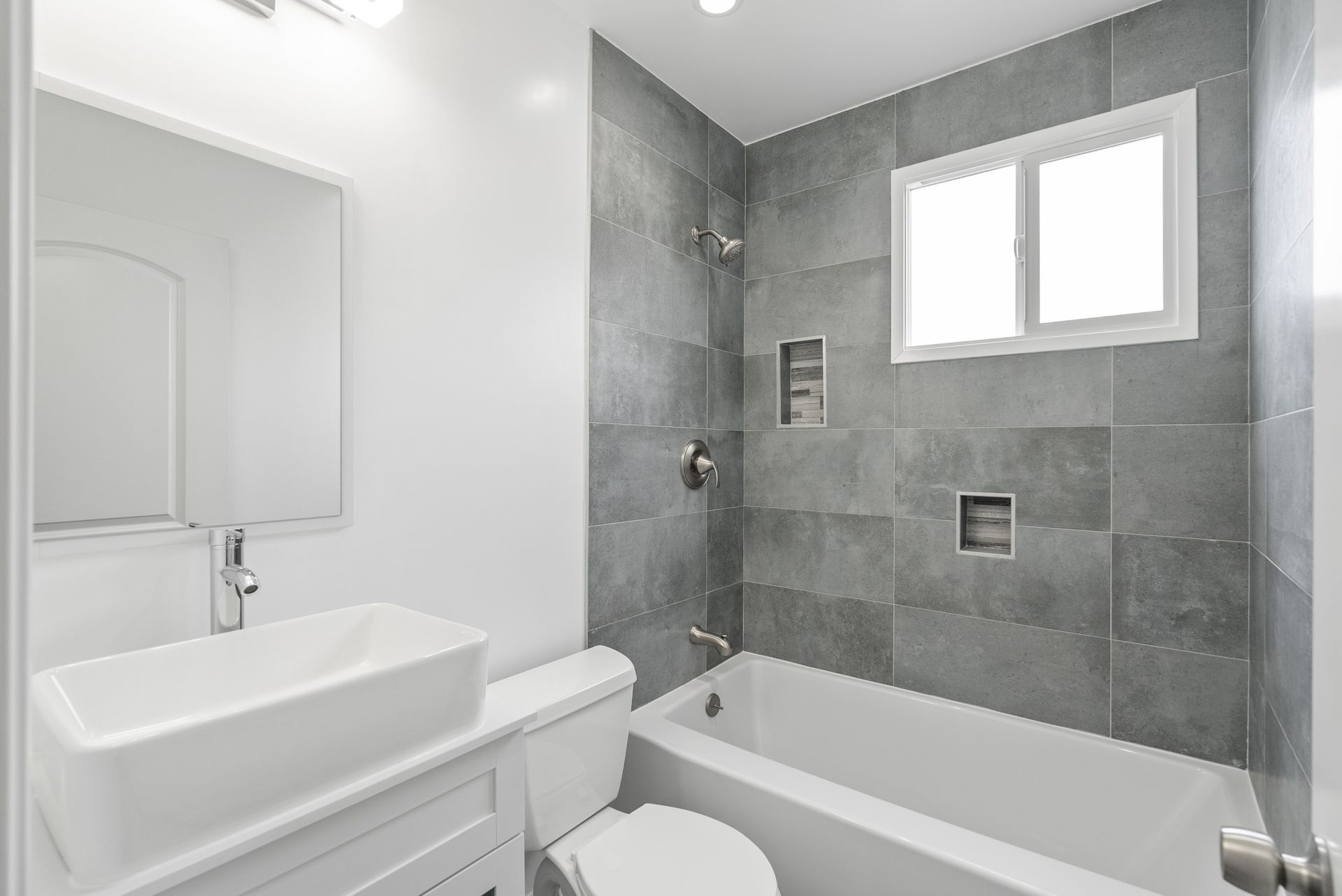 A bathroom with a toilet , sink , tub and mirror.