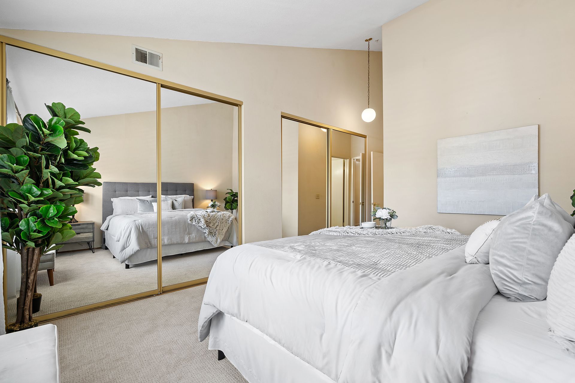 A bedroom with a bed and a large mirror.