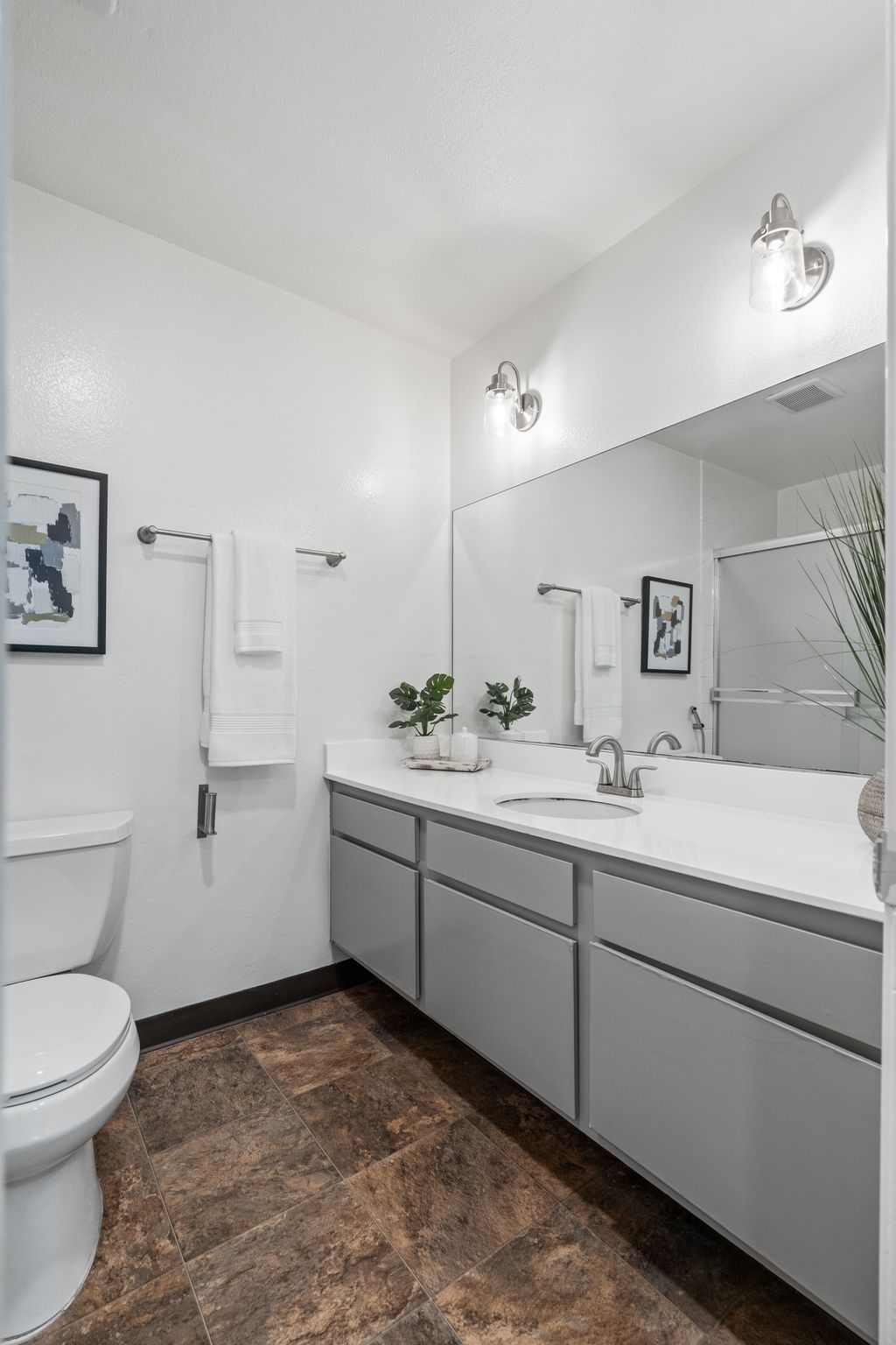 A bathroom with a toilet , sink , and mirror.