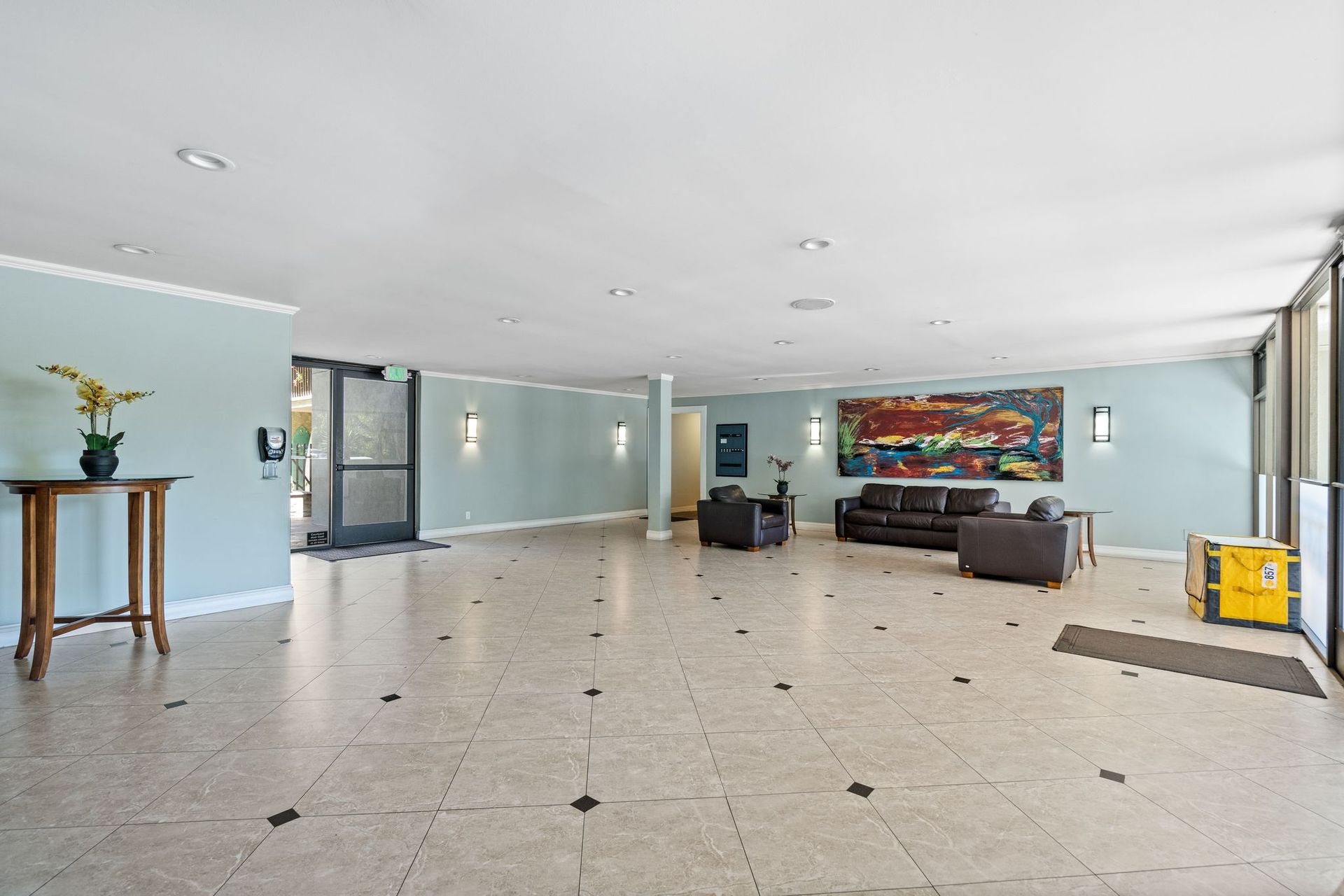 A large room with a couch , chairs , a table and a painting on the wall.