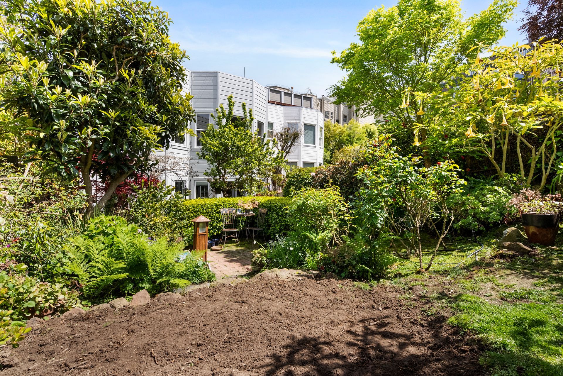 A lush green garden with a residential building in the background.