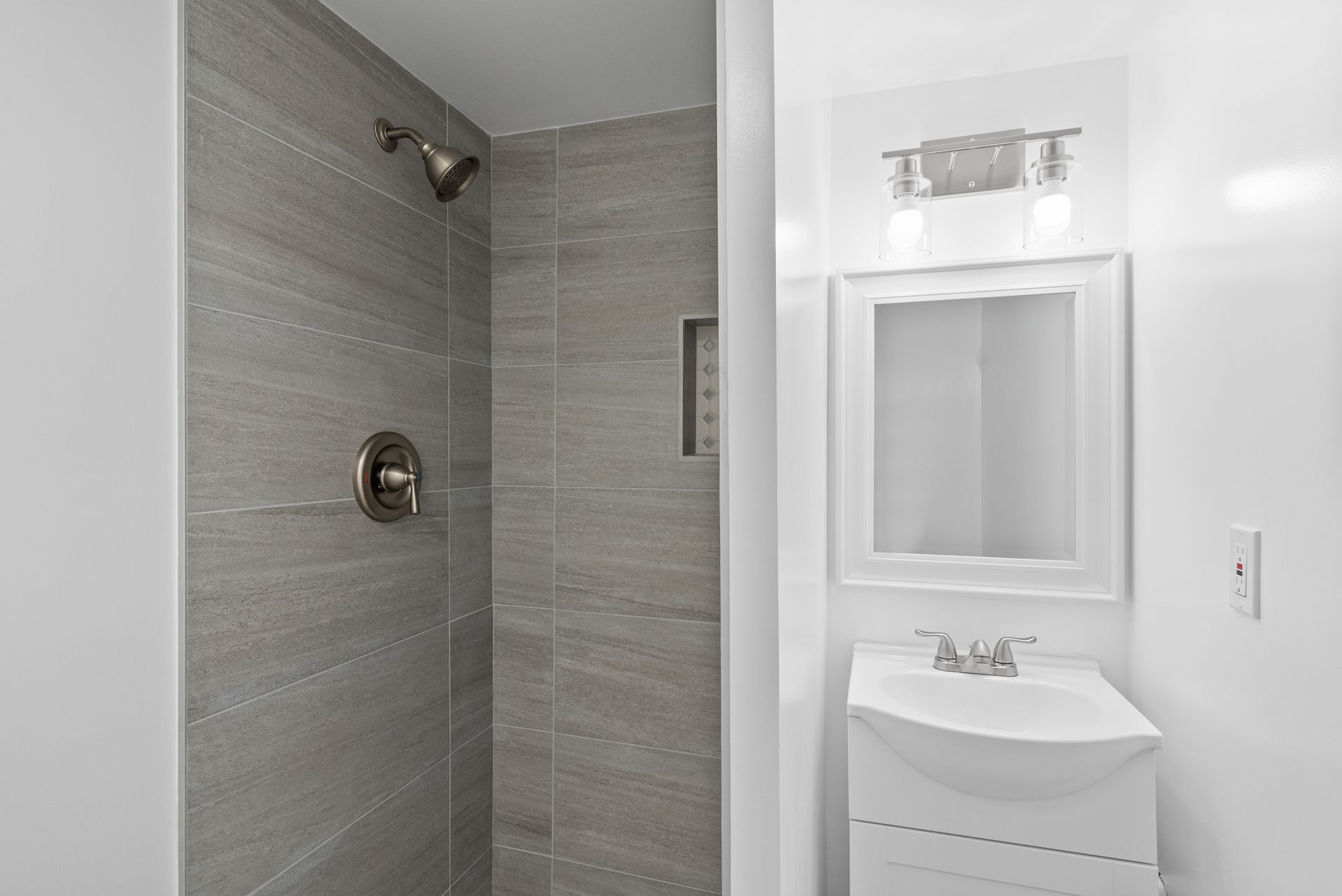 A bathroom with a sink , shower and mirror.