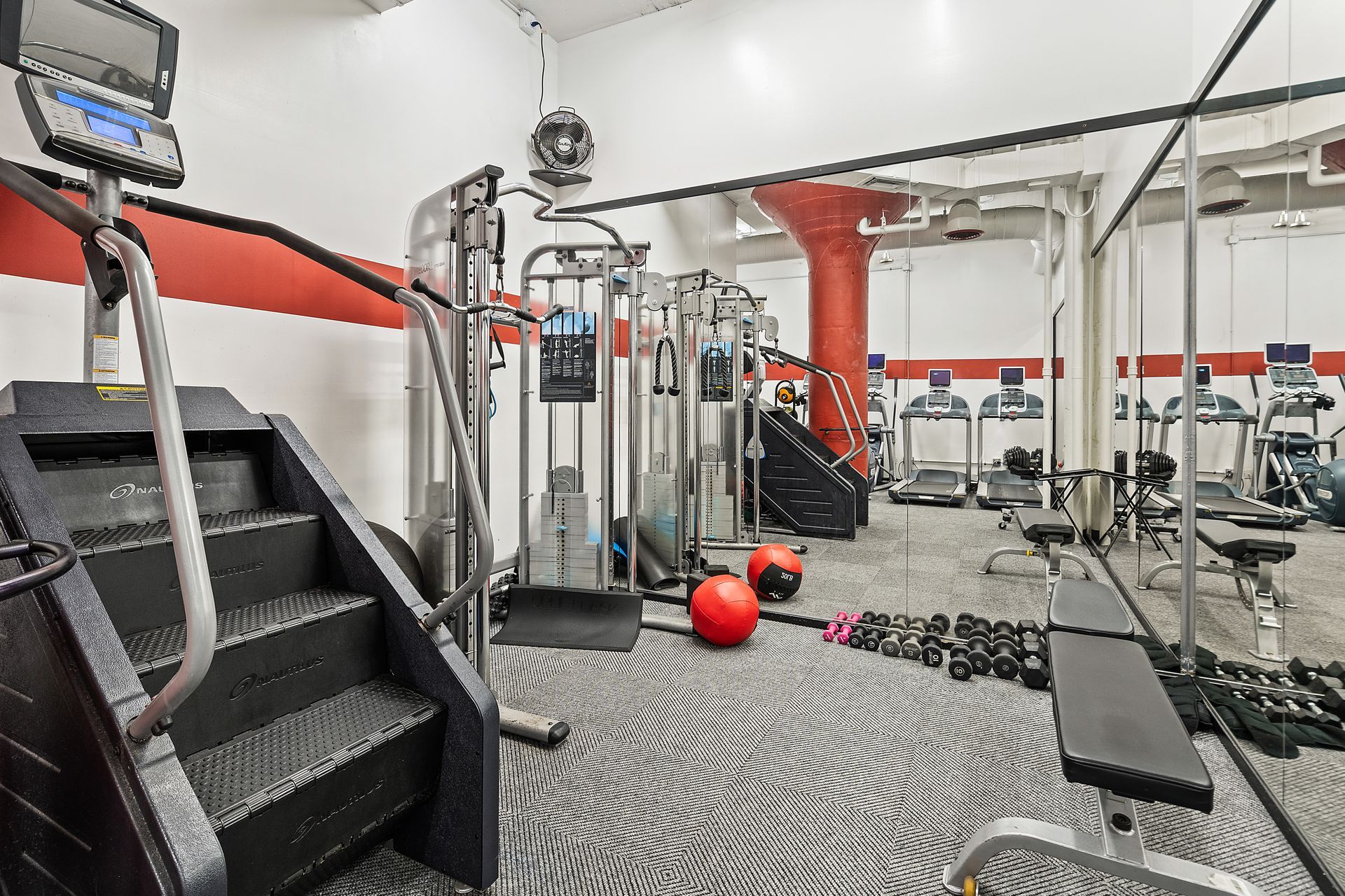 Gym interior with stair stepper, weight machines, treadmills, and free weights.