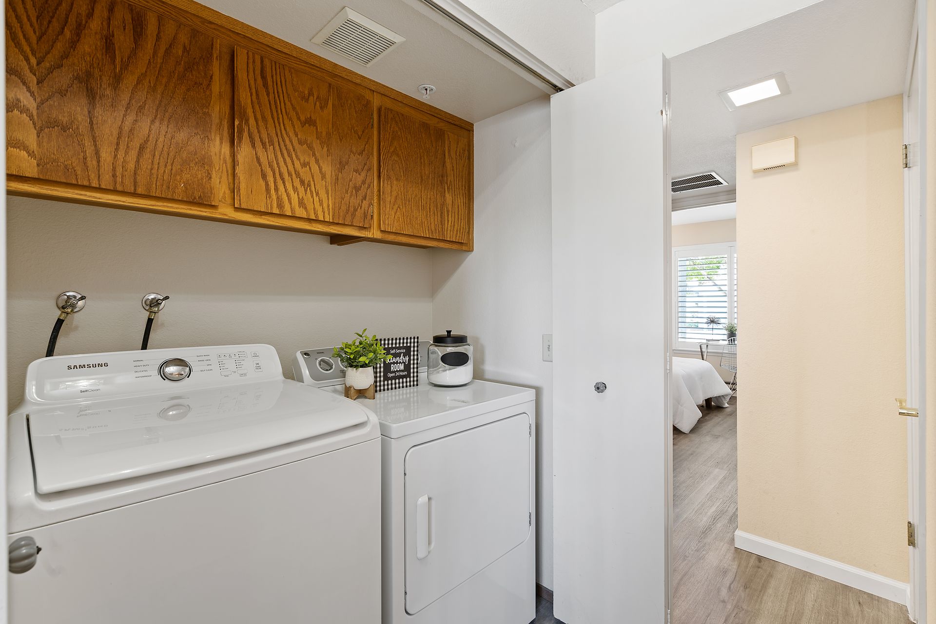 A laundry room with a washer and dryer and a door leading to a bedroom.
