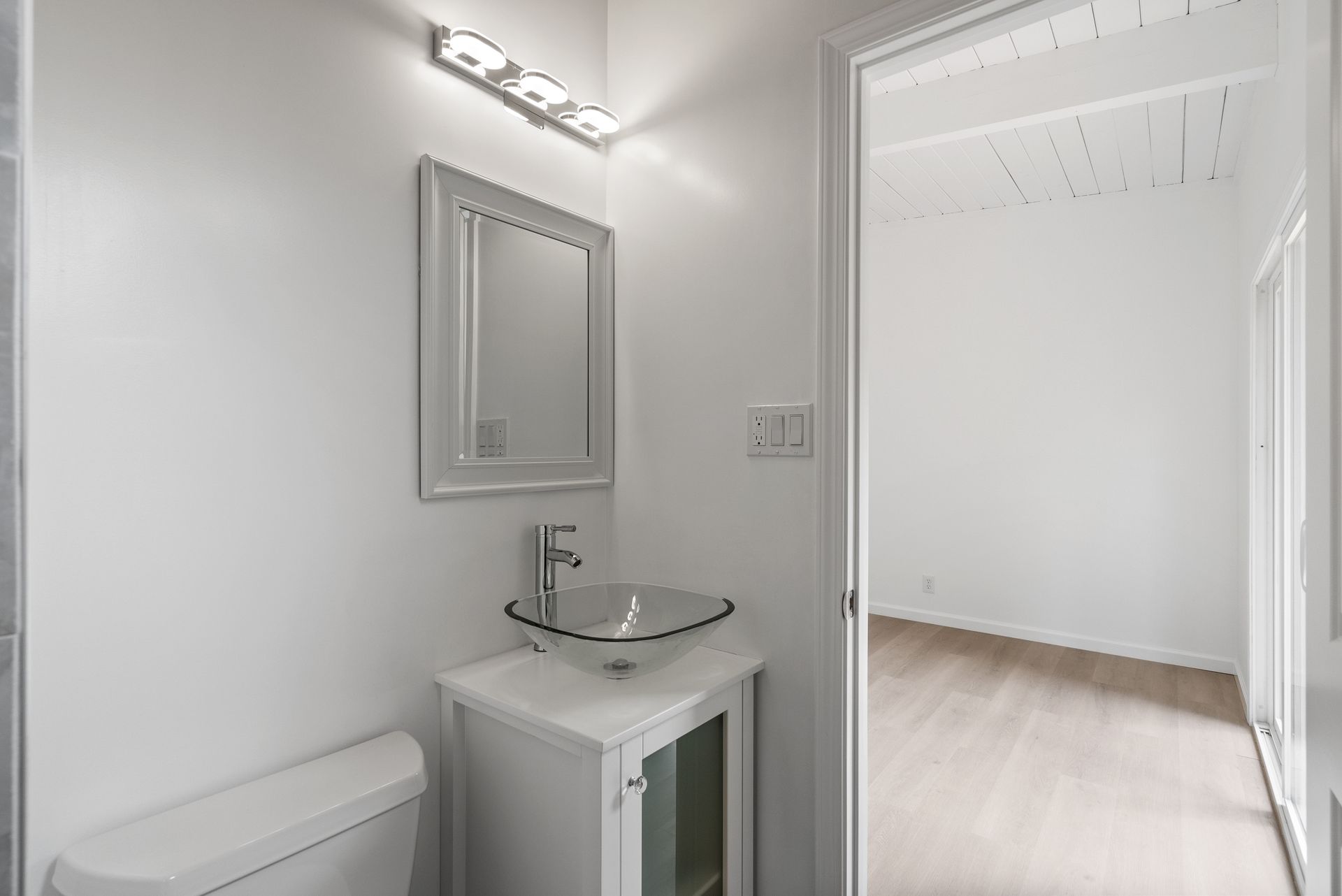 A bathroom with a toilet , sink and mirror.