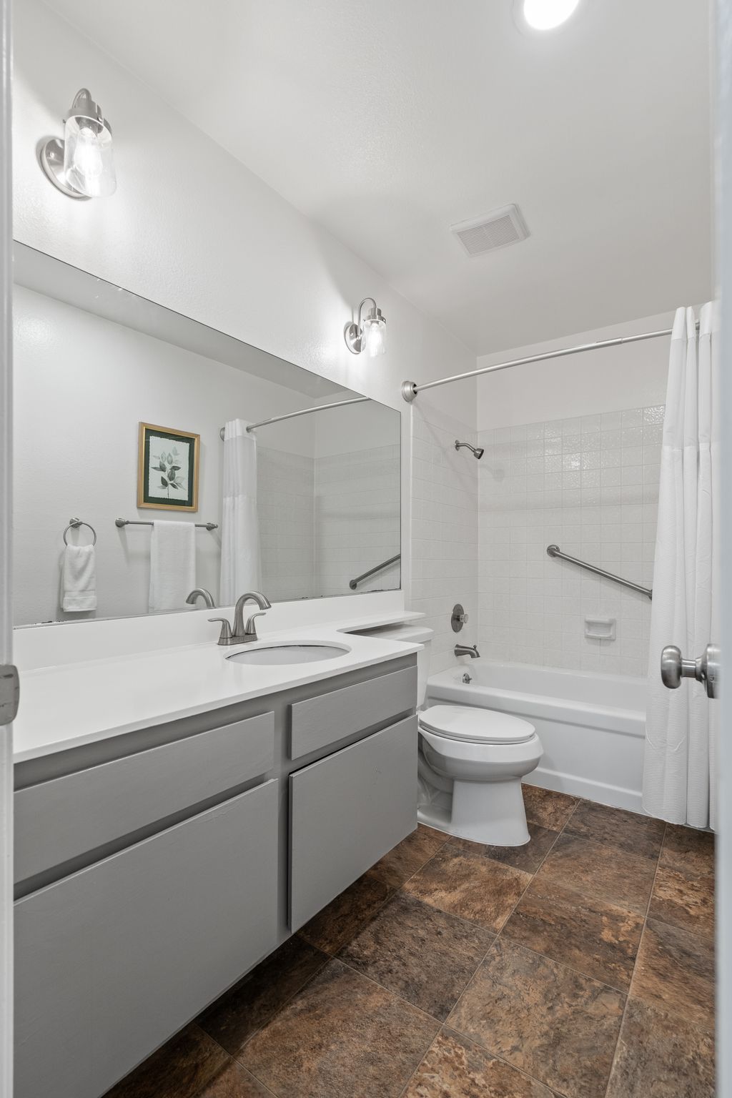 A bathroom with a sink , toilet , tub and mirror.