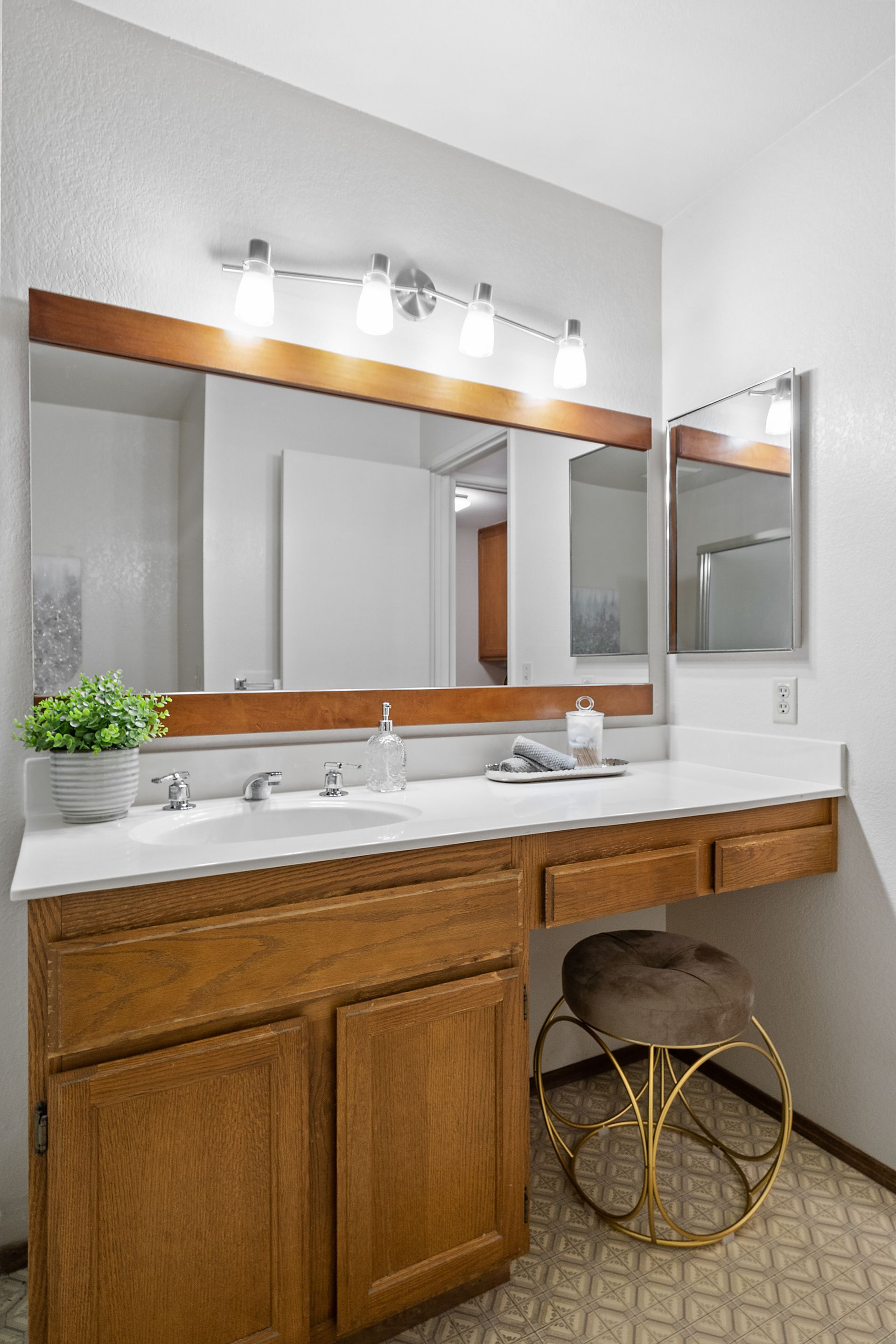 A bathroom with a sink , a mirror and a stool.
