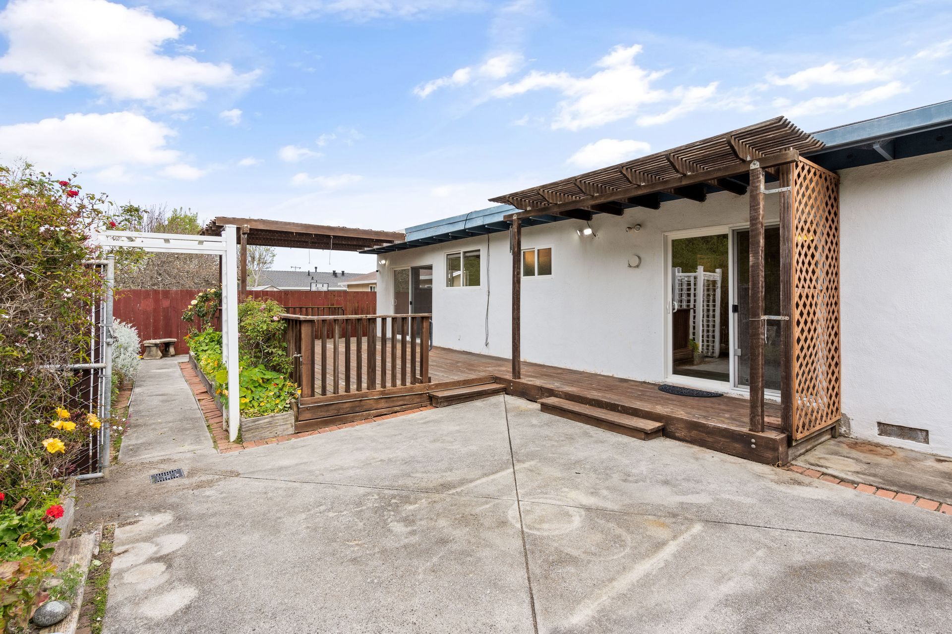 A white house with a wooden deck and a covered porch.
