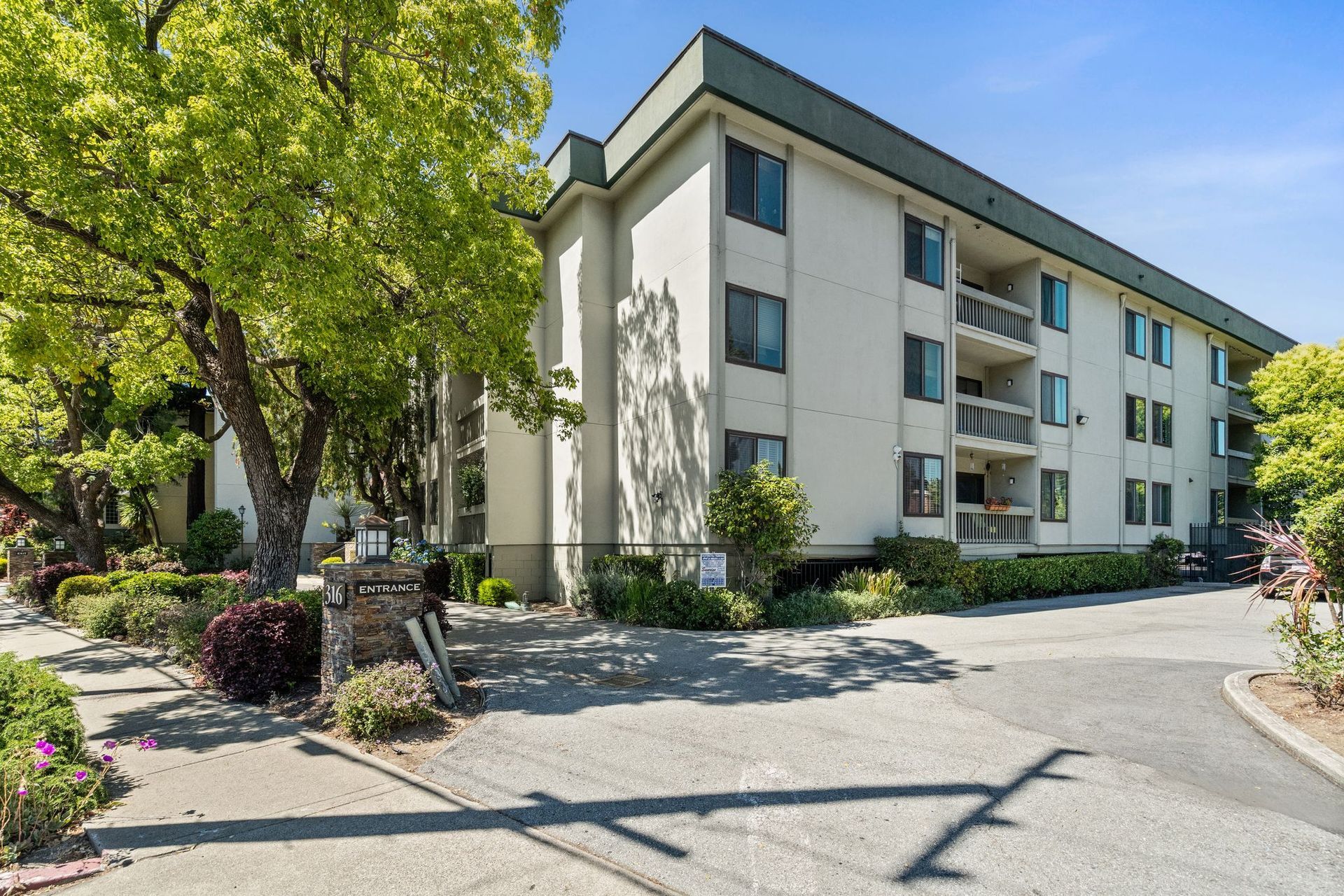 A large condo building with a lot of windows and trees in front of it.