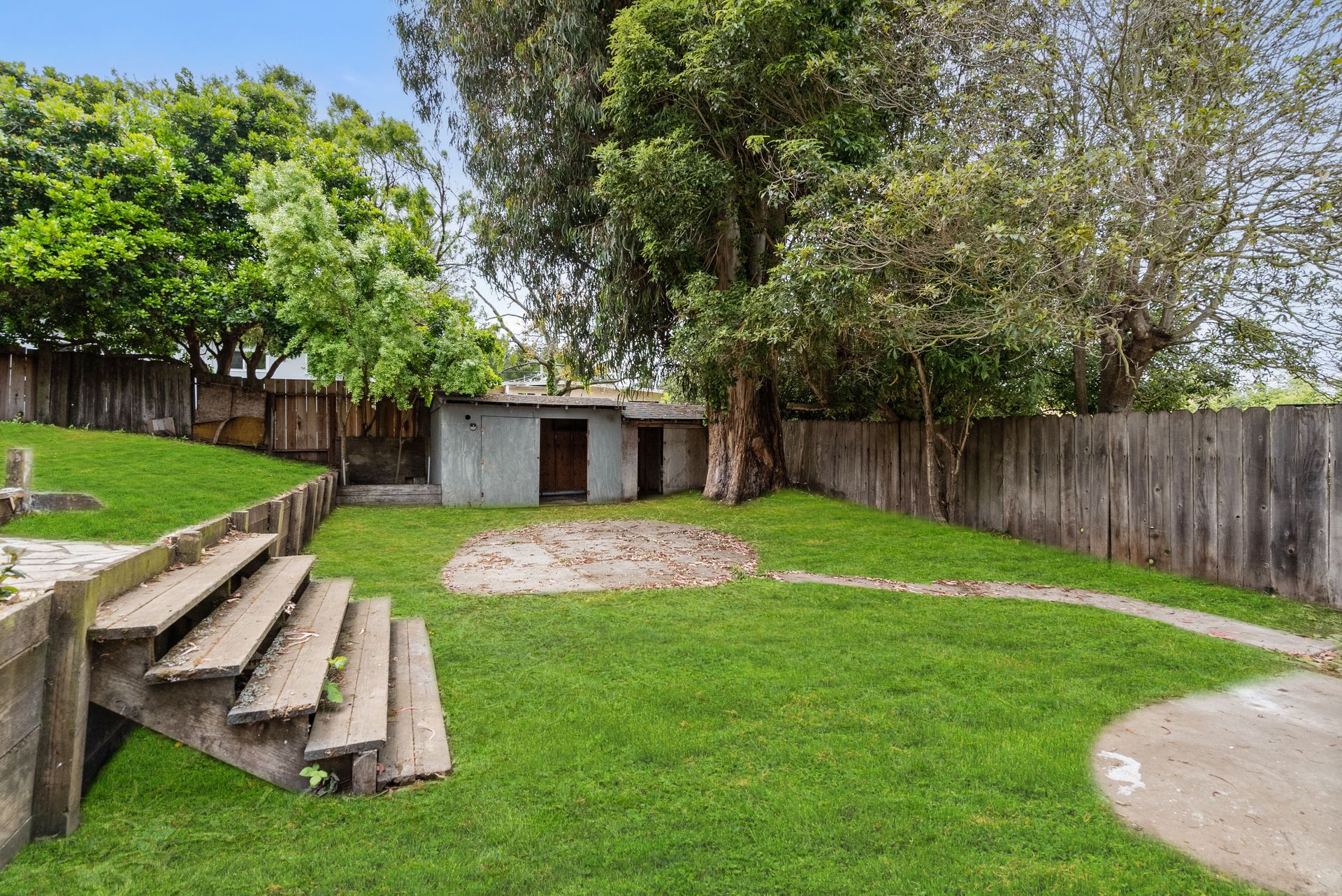 There are stairs leading up to a shed in the backyard.