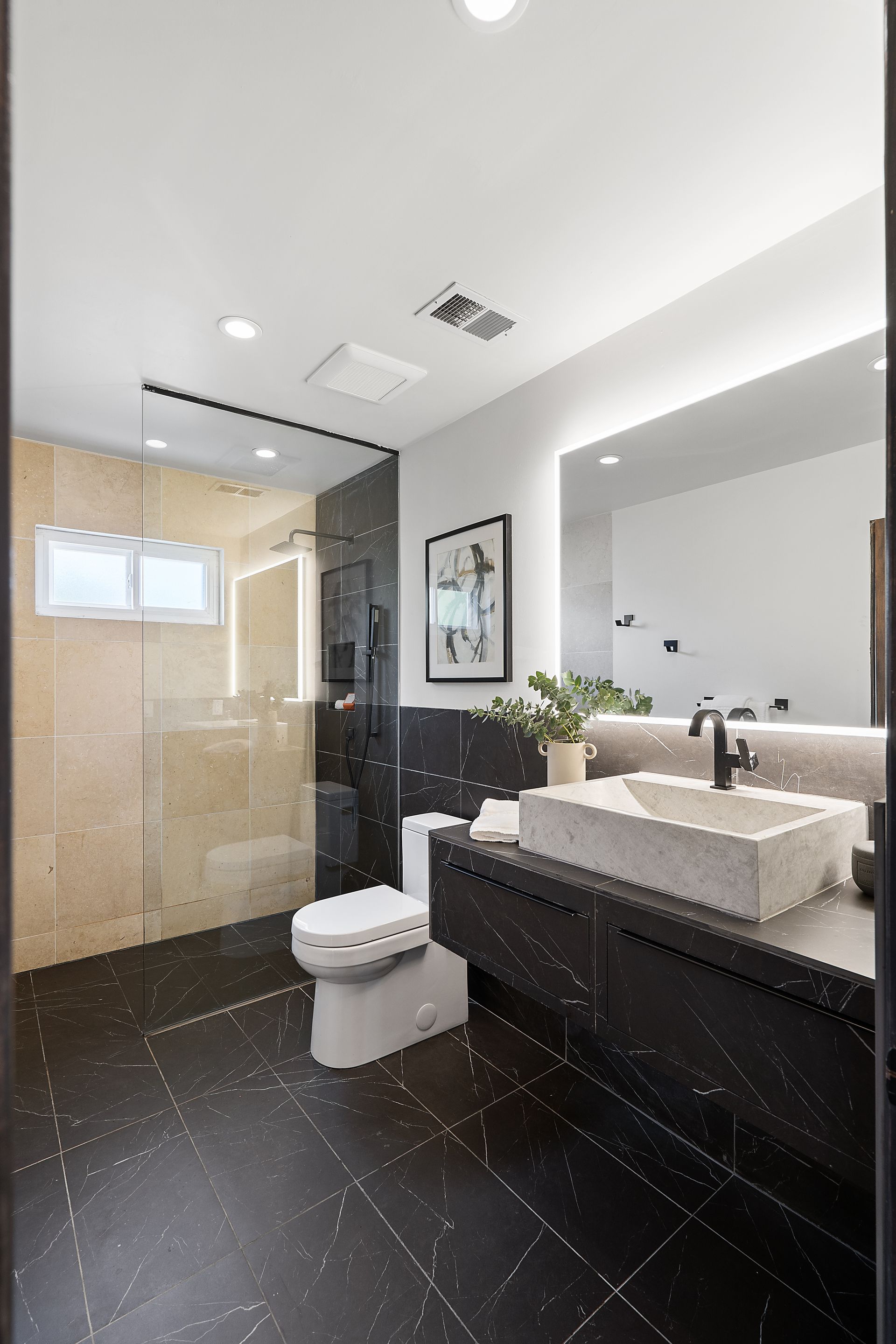 A bathroom with a toilet , sink , mirror and walk in shower.