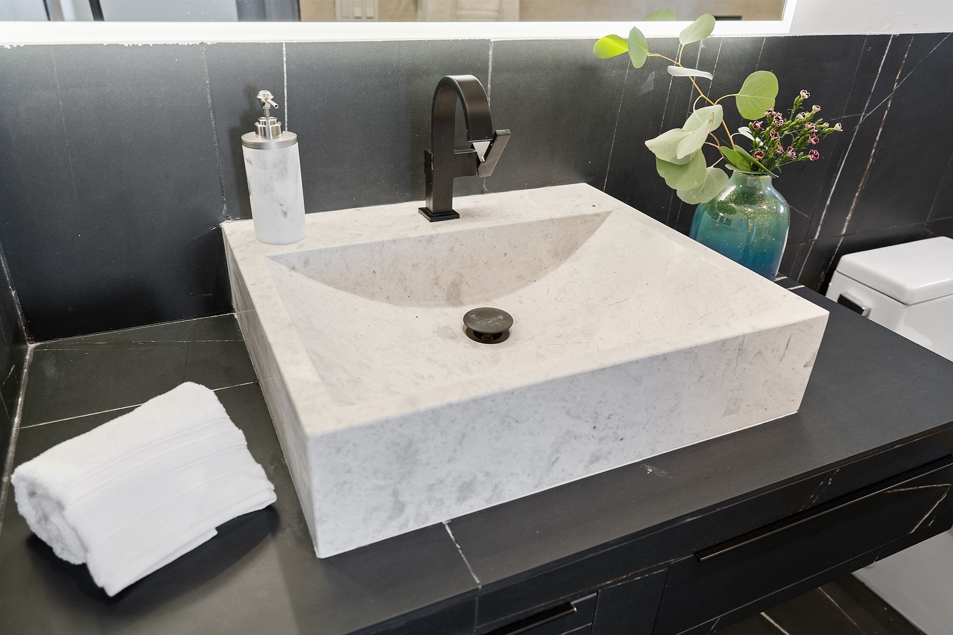 A bathroom sink with a vase of flowers next to it.