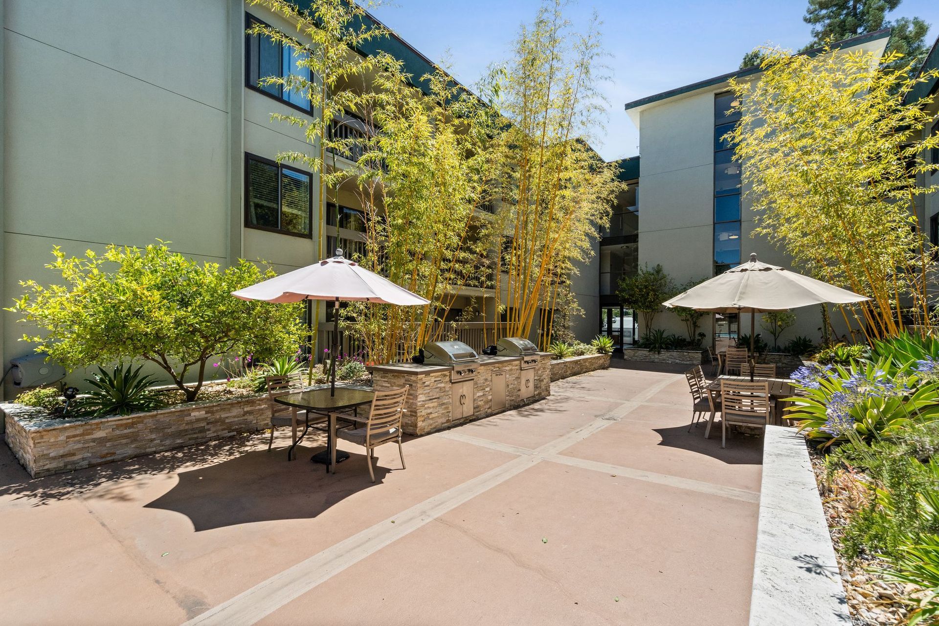 A courtyard with tables and chairs and umbrellas in front of a building.