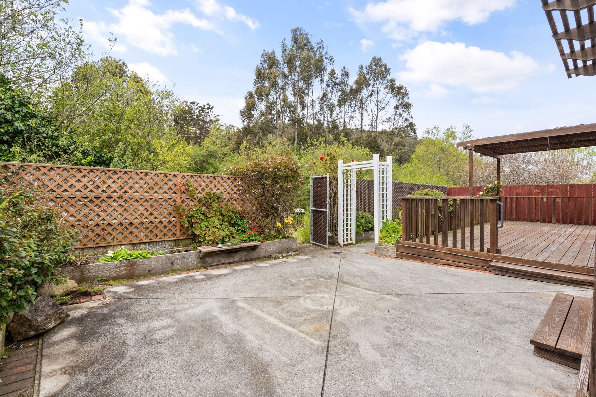 A backyard with a wooden deck and a wooden fence.