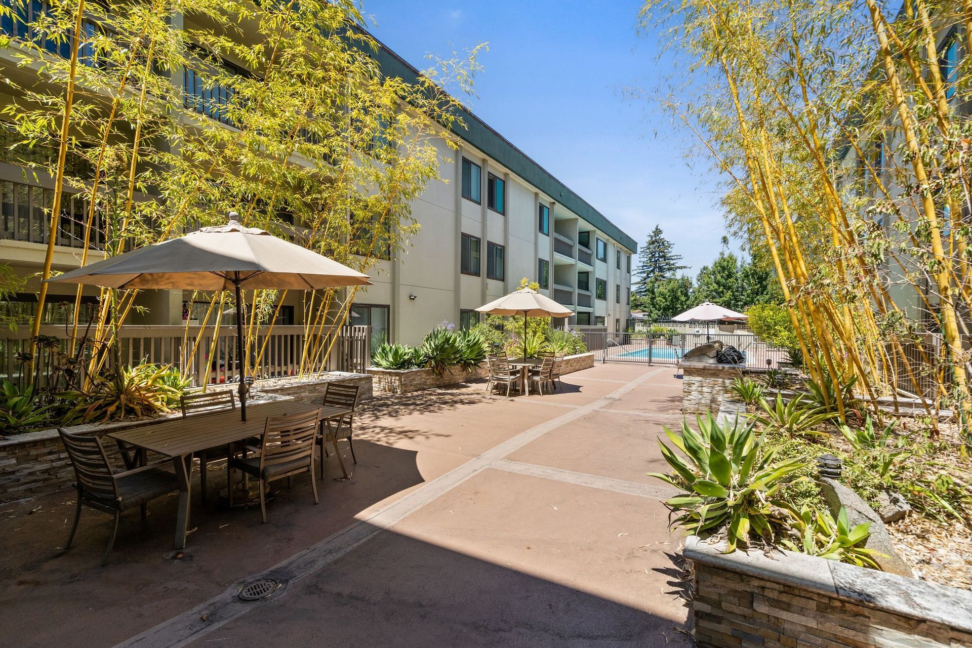 A patio area with tables and chairs and umbrellas in front of a building.