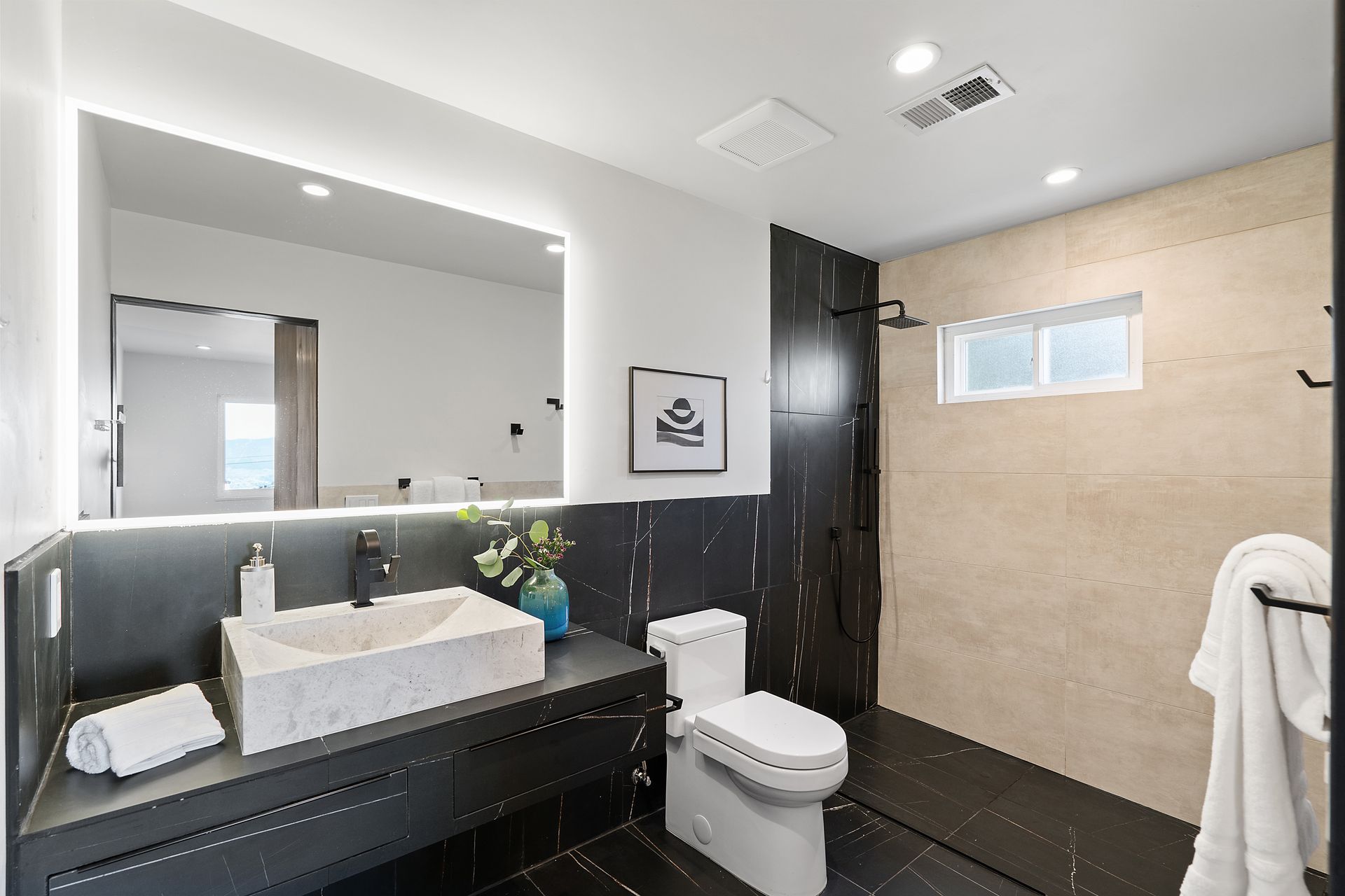 A bathroom with a toilet , sink, shower stall and mirror.