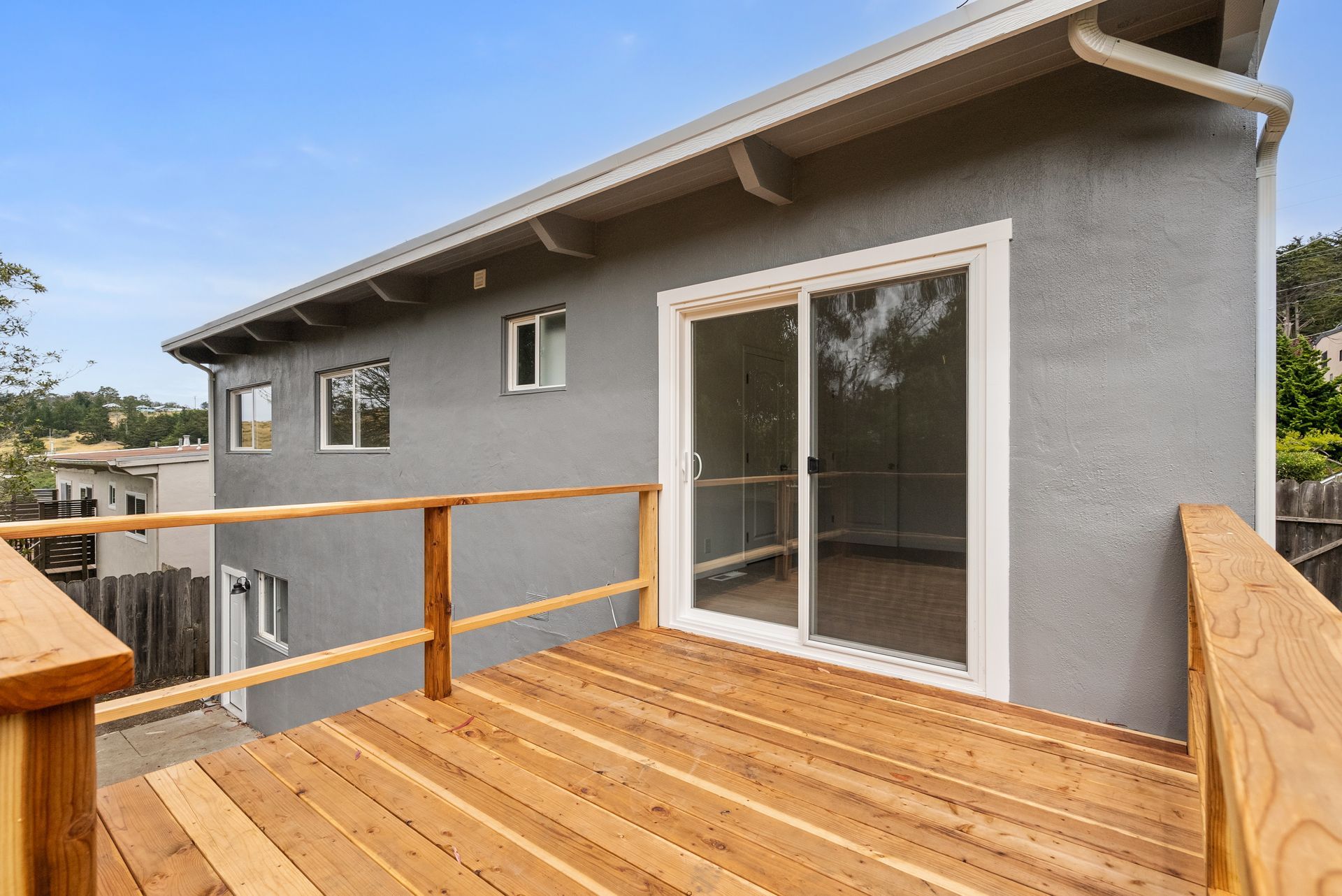 There is a wooden deck in front of a house with a sliding glass door.