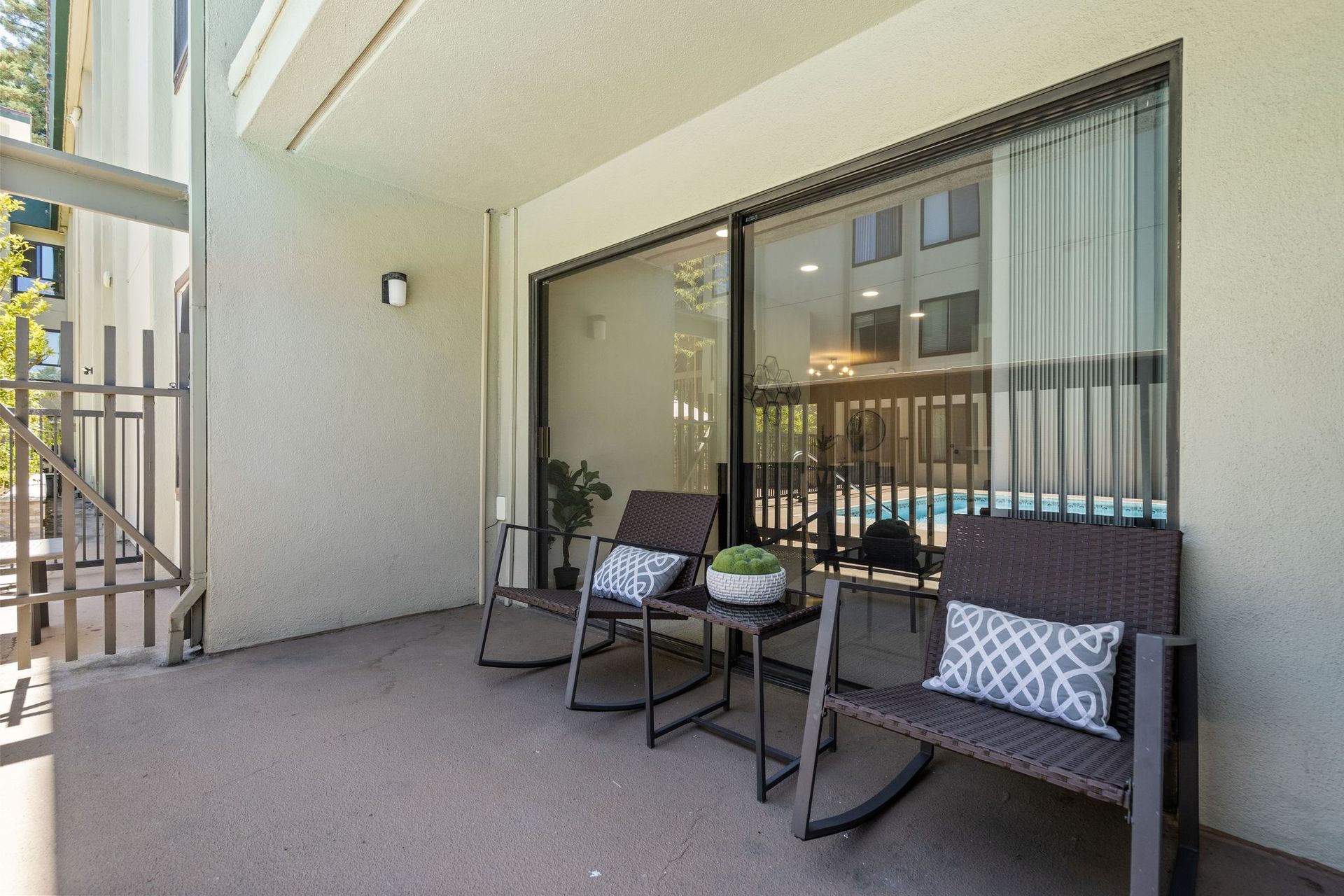 There are two rocking chairs and a table on the balcony.