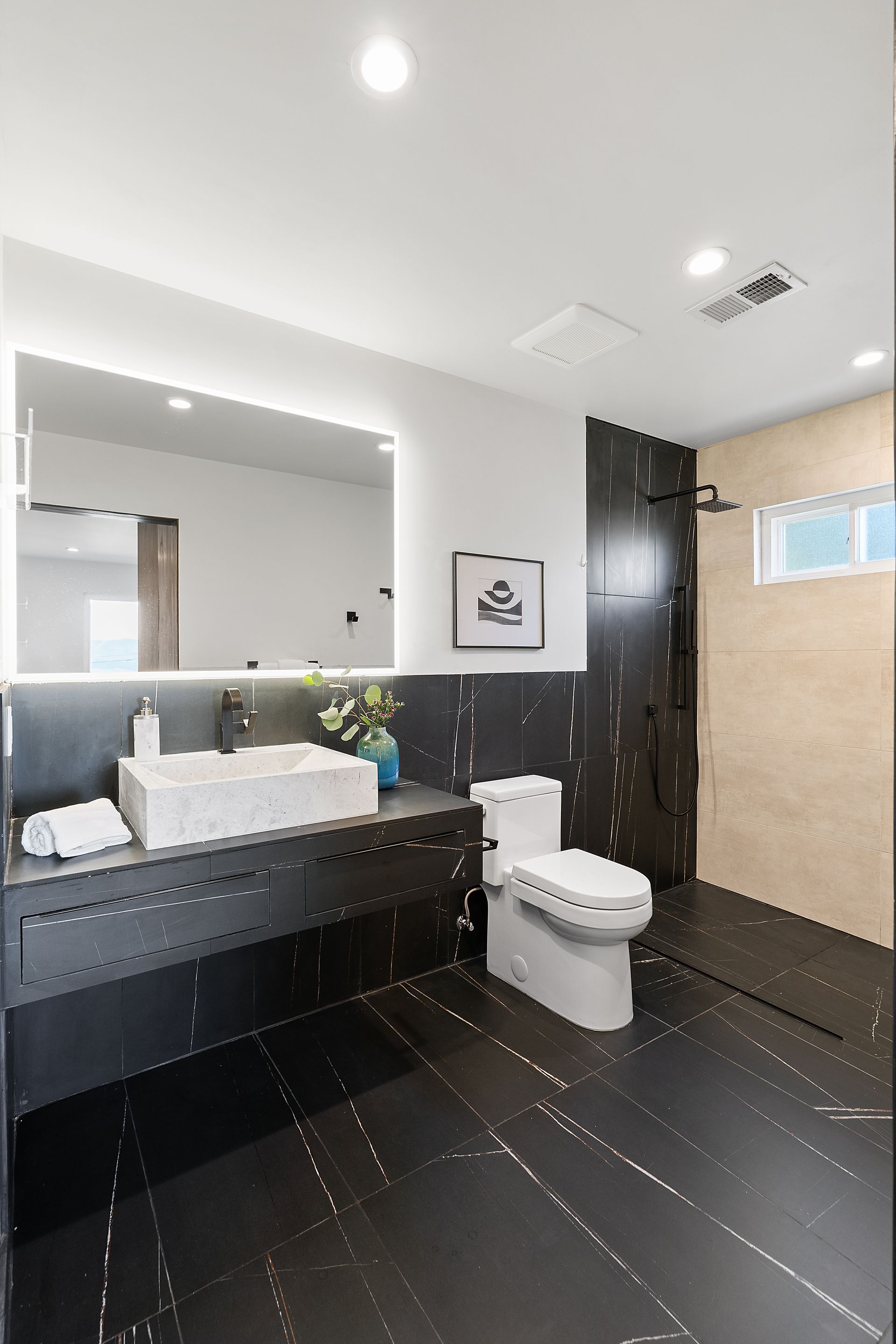 A bathroom with a toilet , sink, shower stall and mirror.
