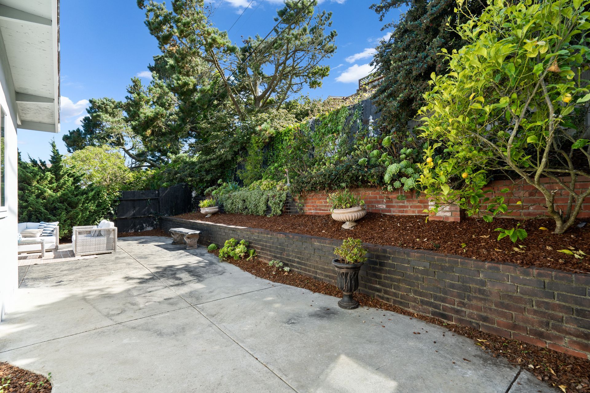 A patio with a brick wall and trees in the background.