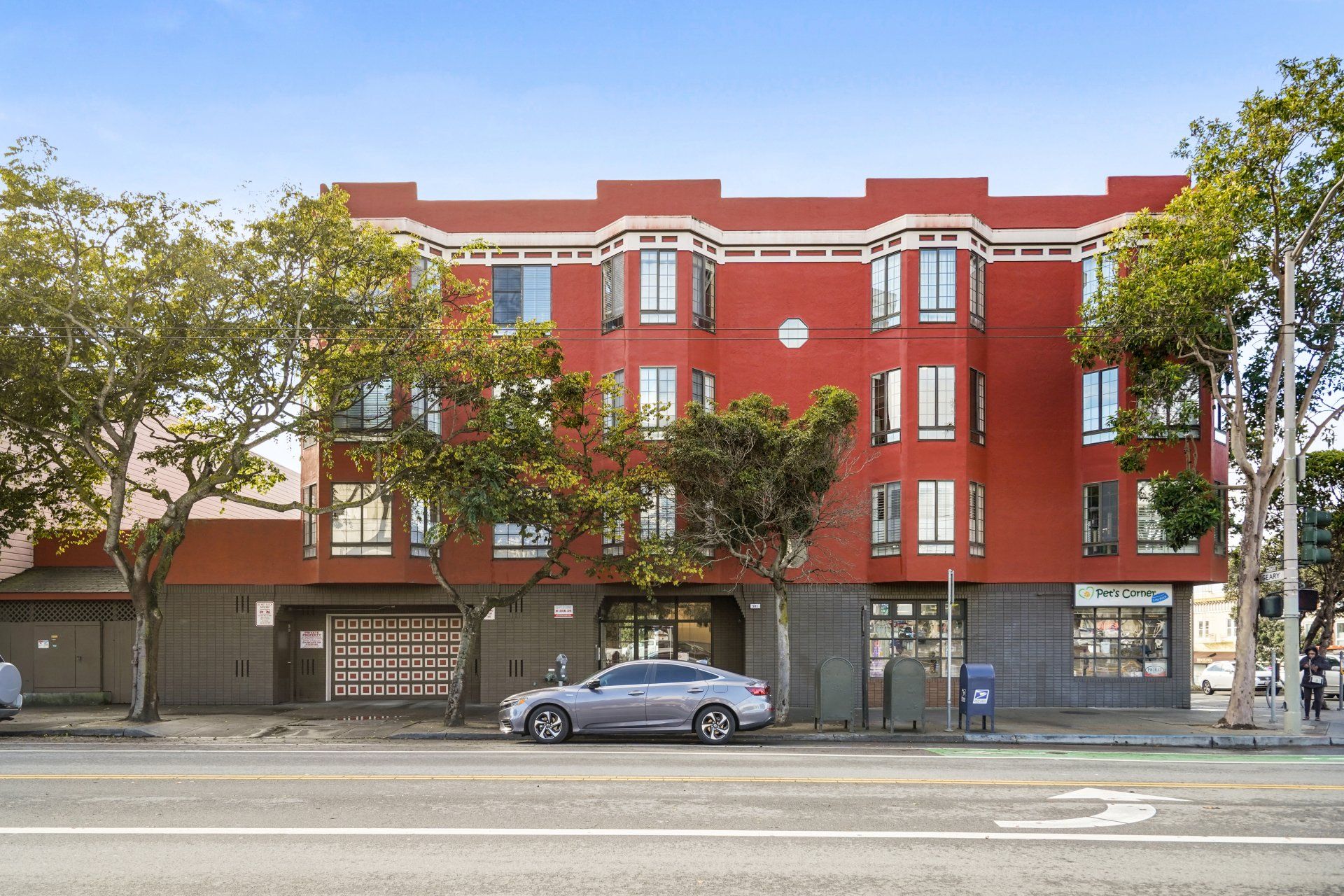 A car is parked in front of a red building.
