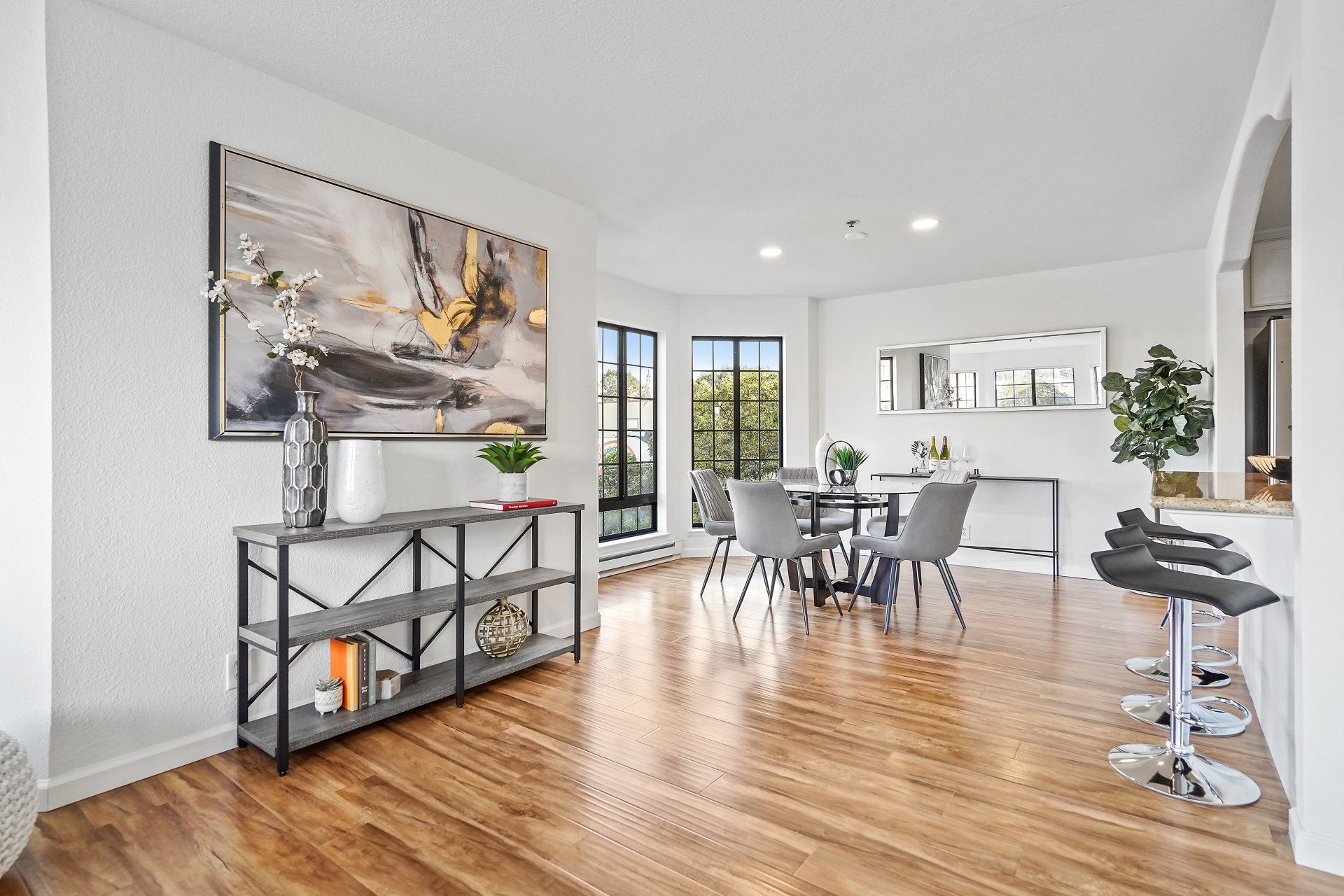 A living room with hardwood floors , a table and chairs , and a painting on the wall.